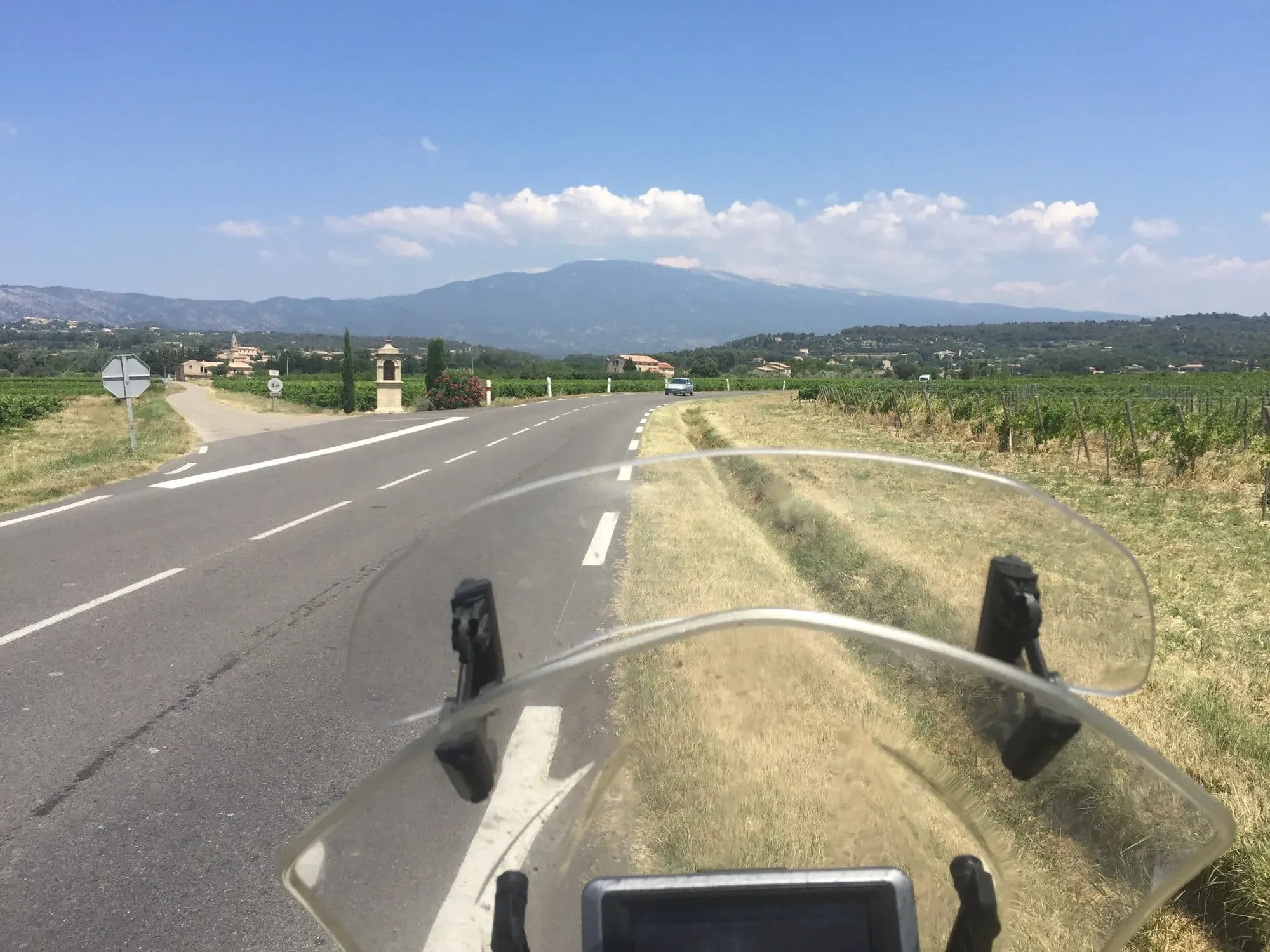 Motorcycle windscreen view of Italian countryside road with mountain