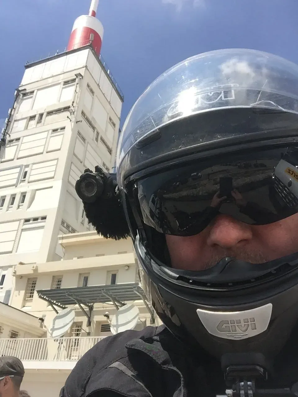 Motorcyclist in helmet with tower and antenna in background