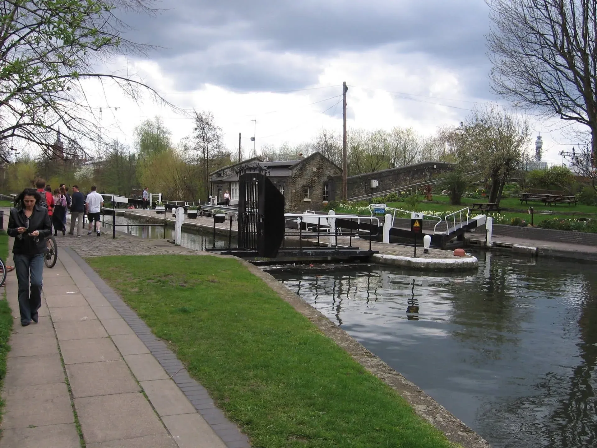 Canal lock with brick keeper's cottage and moored narrowboats on sunny day