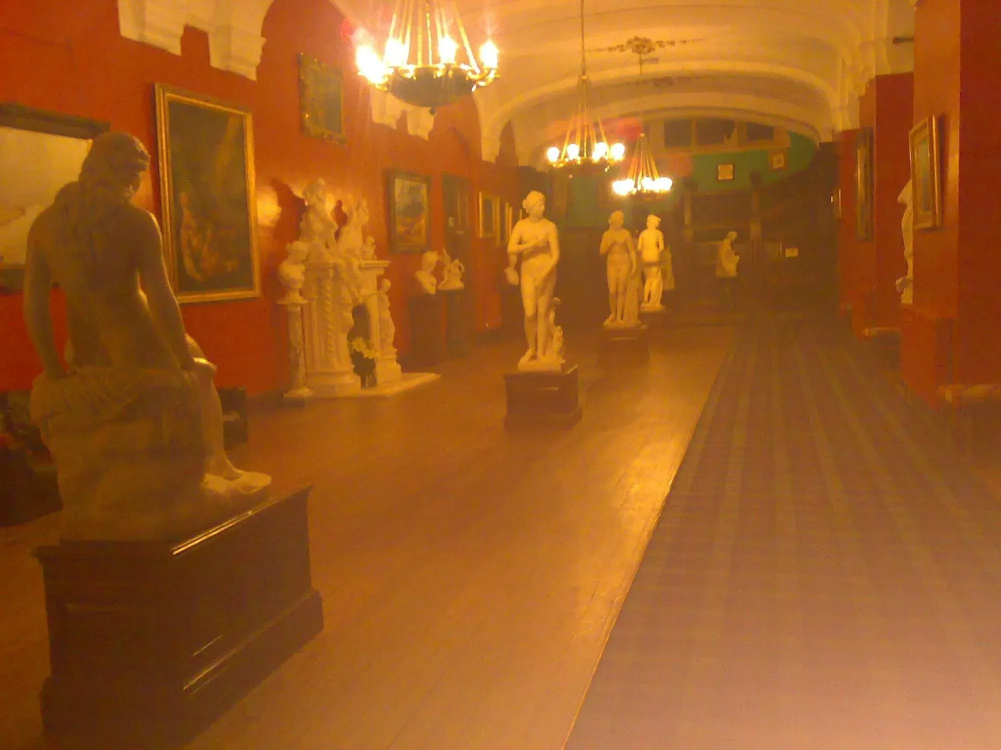 Museum gallery with classical statues and warm orange lighting
