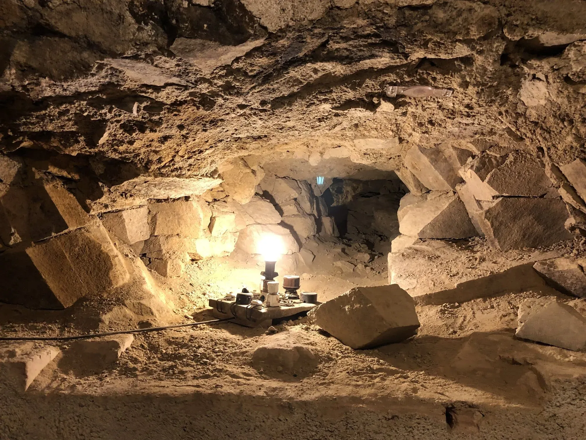 Underground cave chamber with lanterns and archaeological excavation equipment