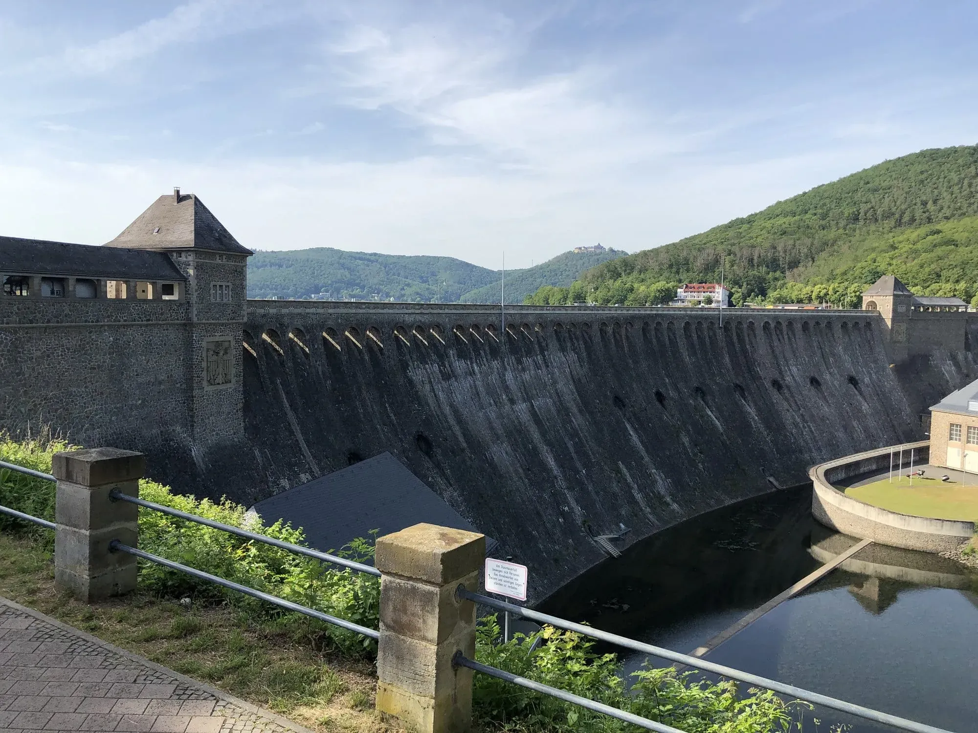 Historic stone dam with tower in forested river valley