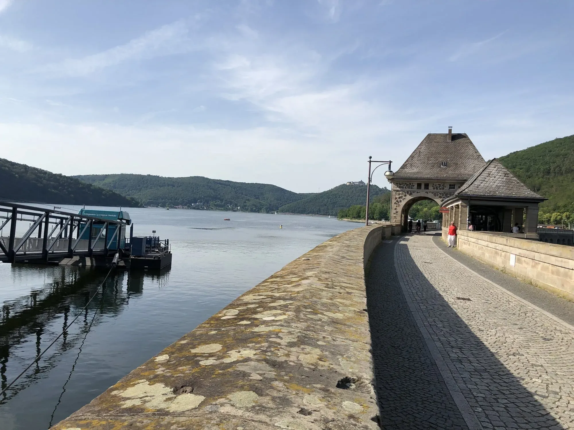 Lakeside promenade with historic stone gatehouse and moored boat