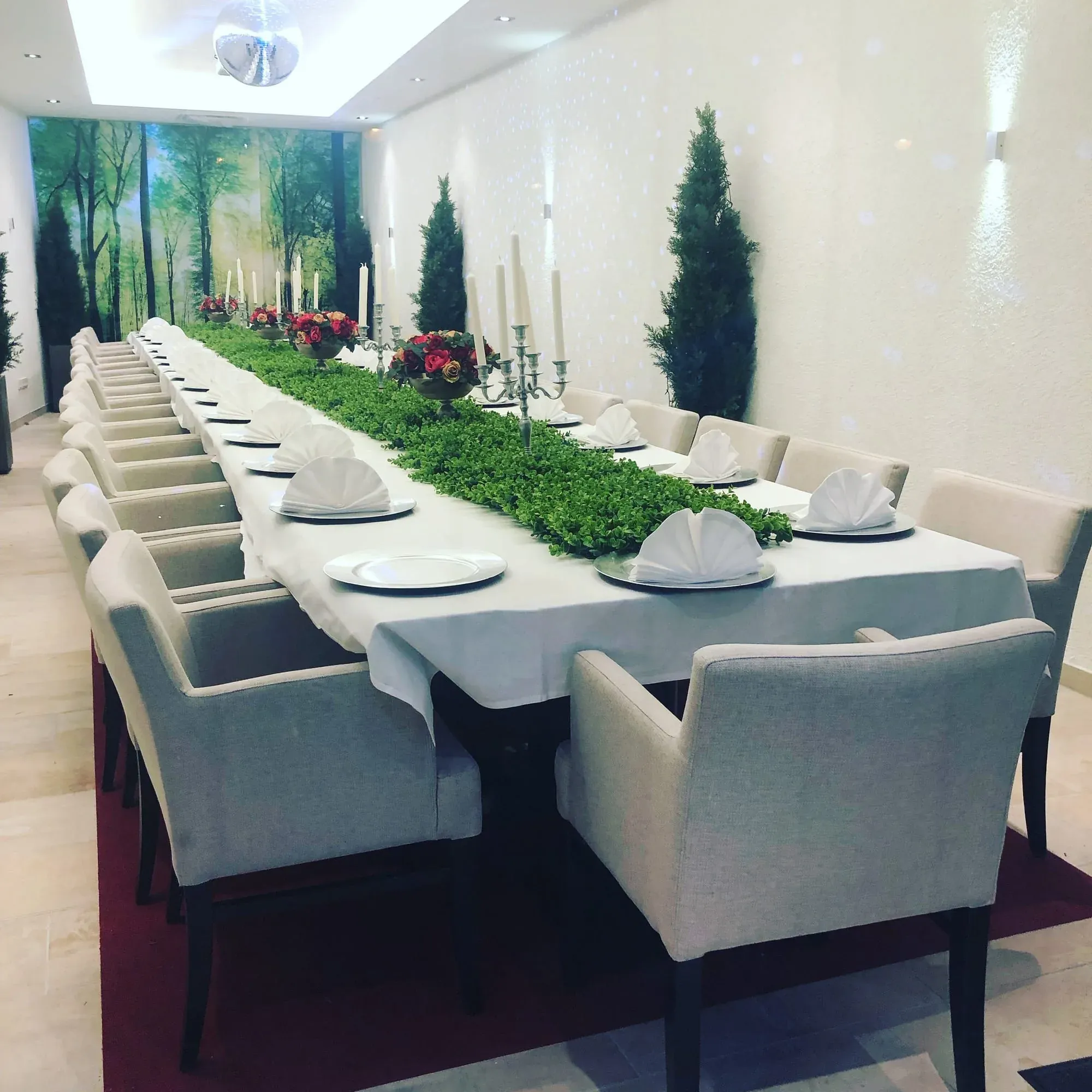 Formal dining room with long white table and green plant centerpiece