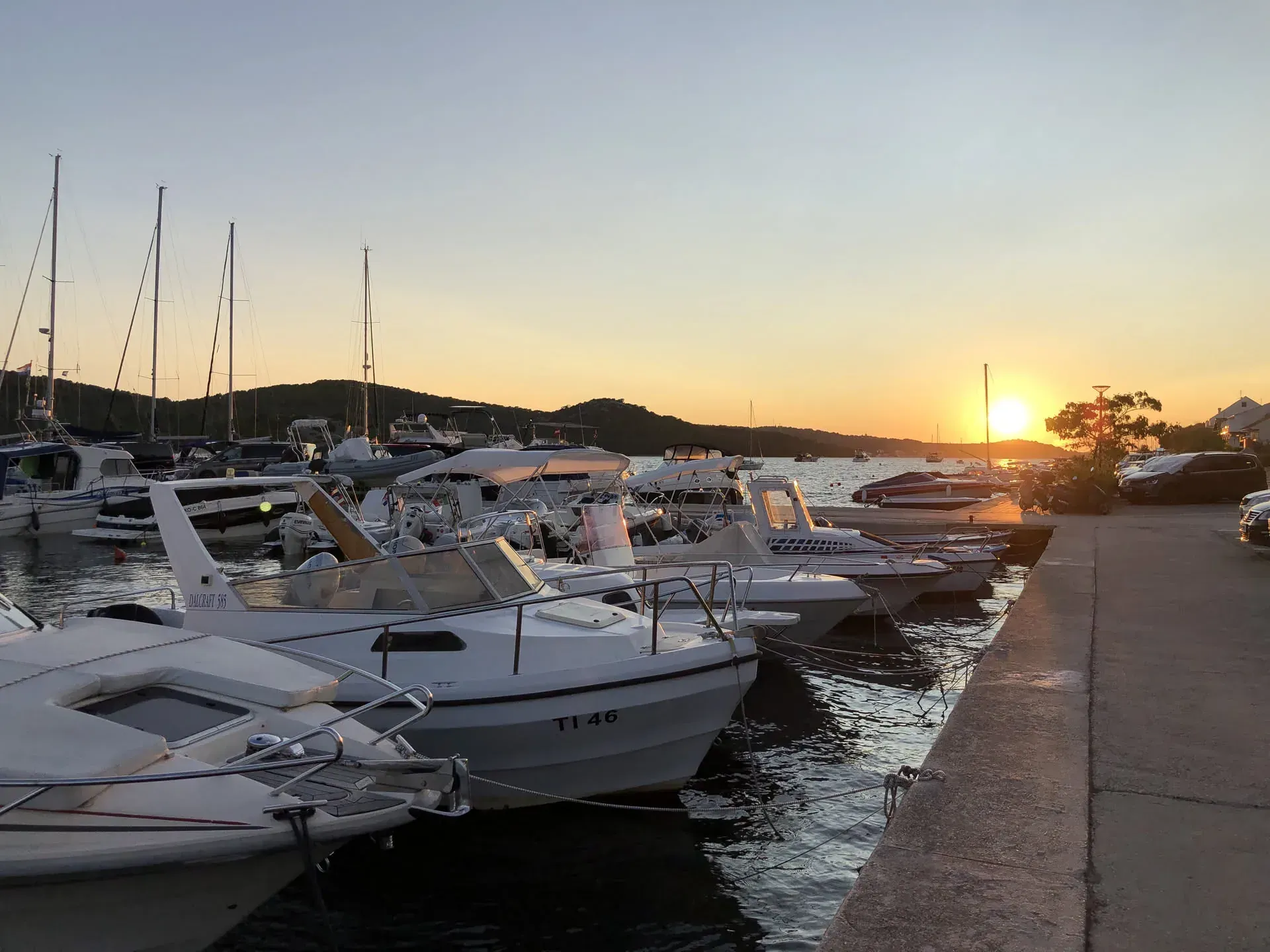 Sailboats moored at sunset in Tisno harbor