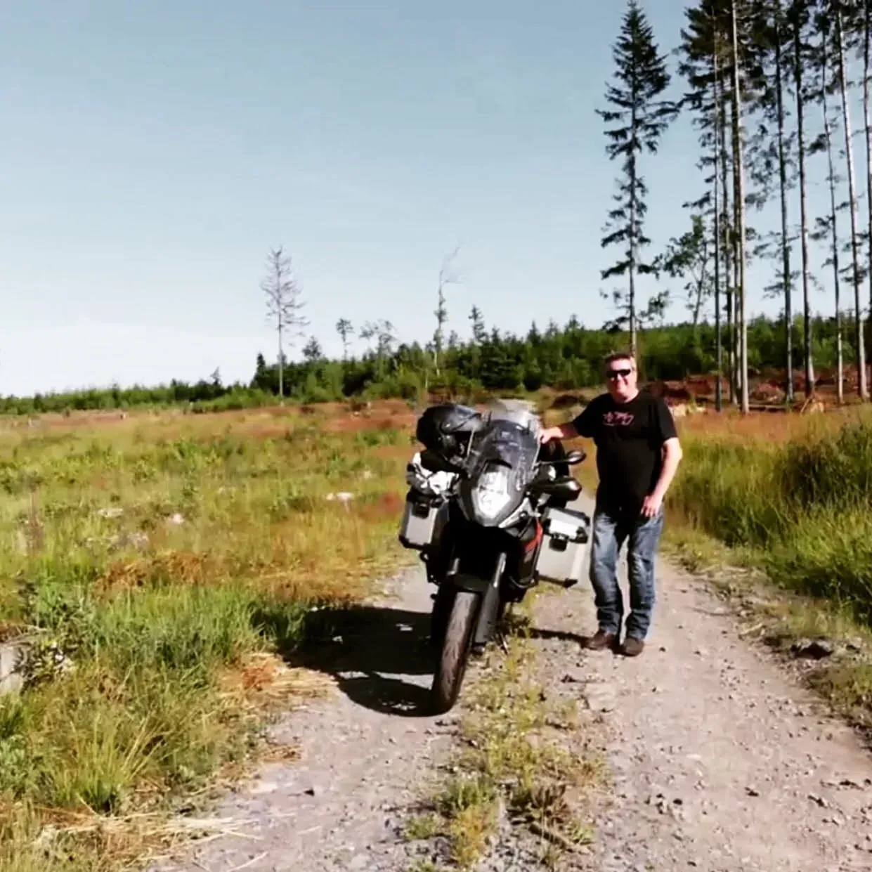 Two men with motorcycle on dirt road, Moravská
