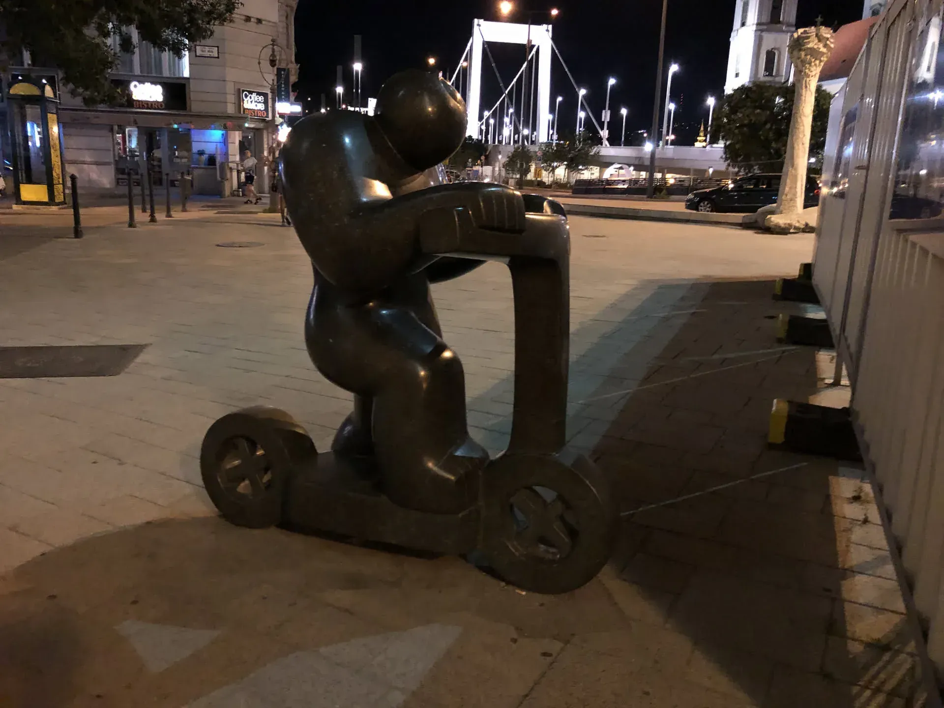 Black sculpture of figure on scooter, Belváros Budapest at night