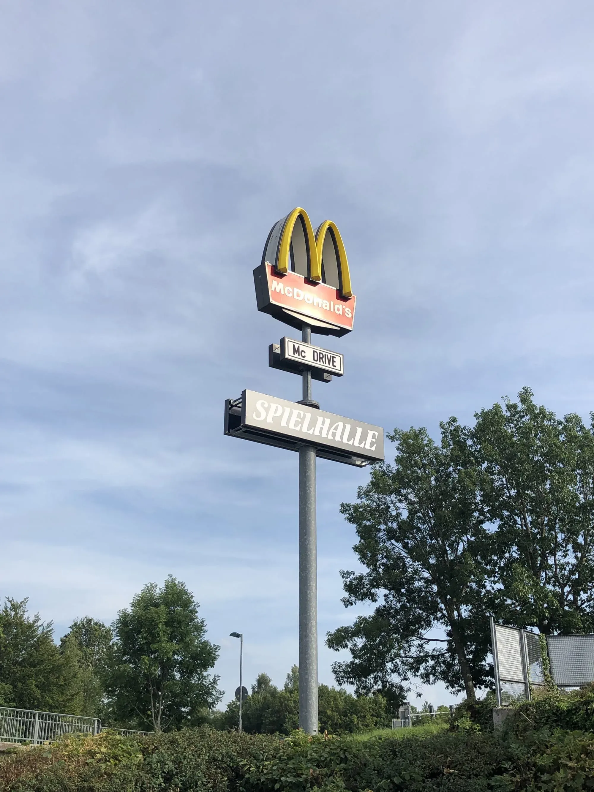 McDonald's golden arches sign with Spielhalle and McDrive street signs below