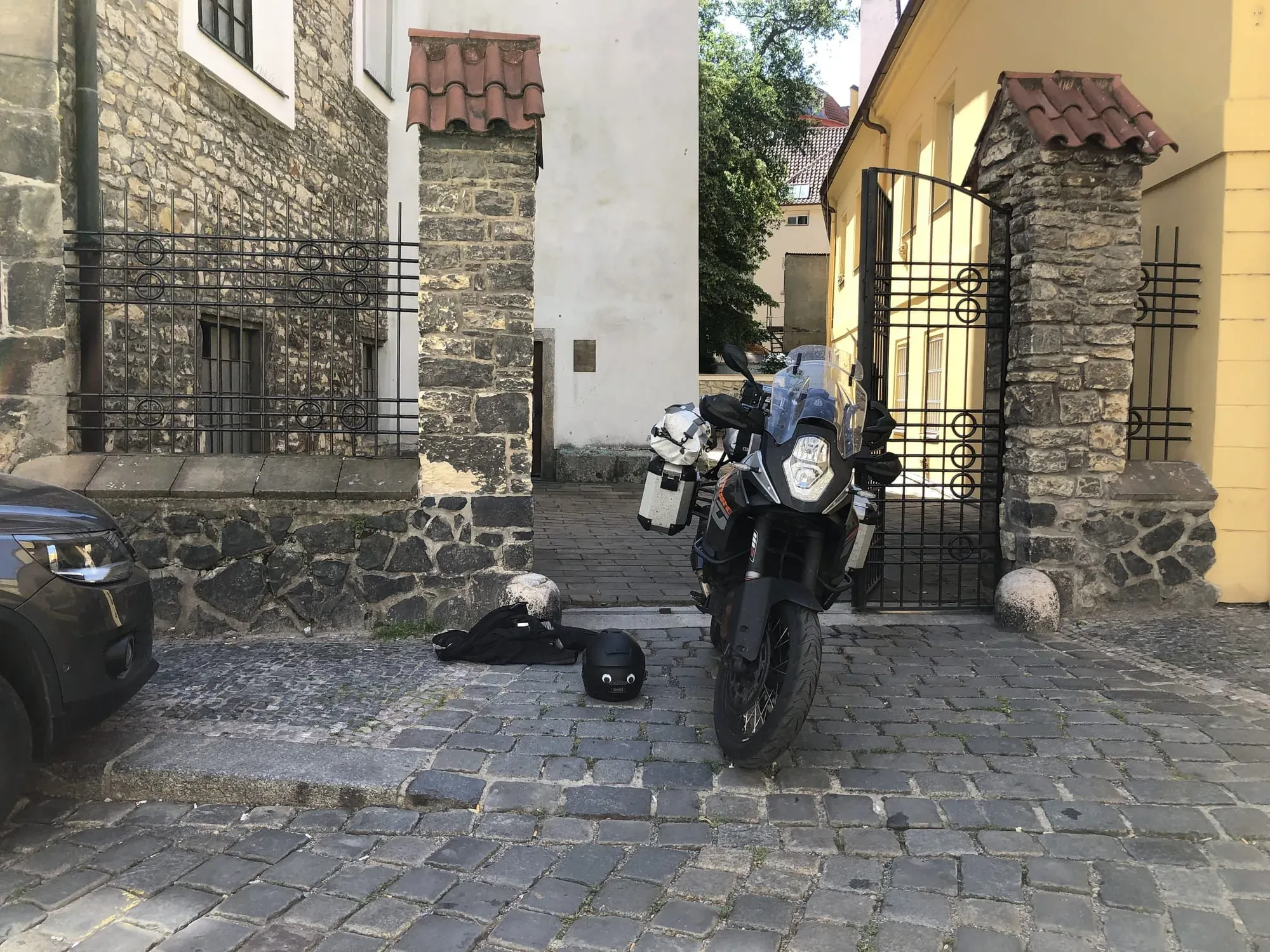 Black and white motorcycle parked in historic stone courtyard with gates