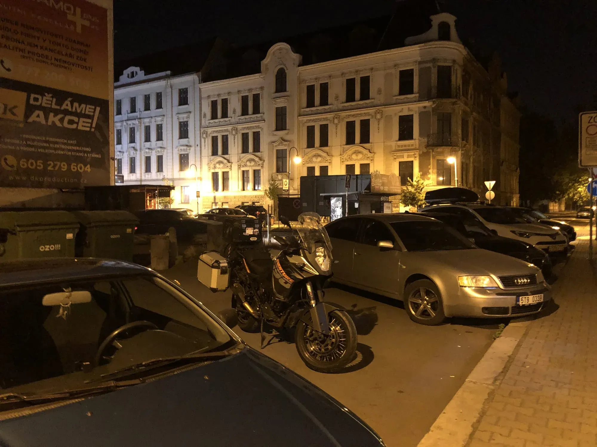 Motorcycle with sidecar parked at night in front of illuminated historic buildings