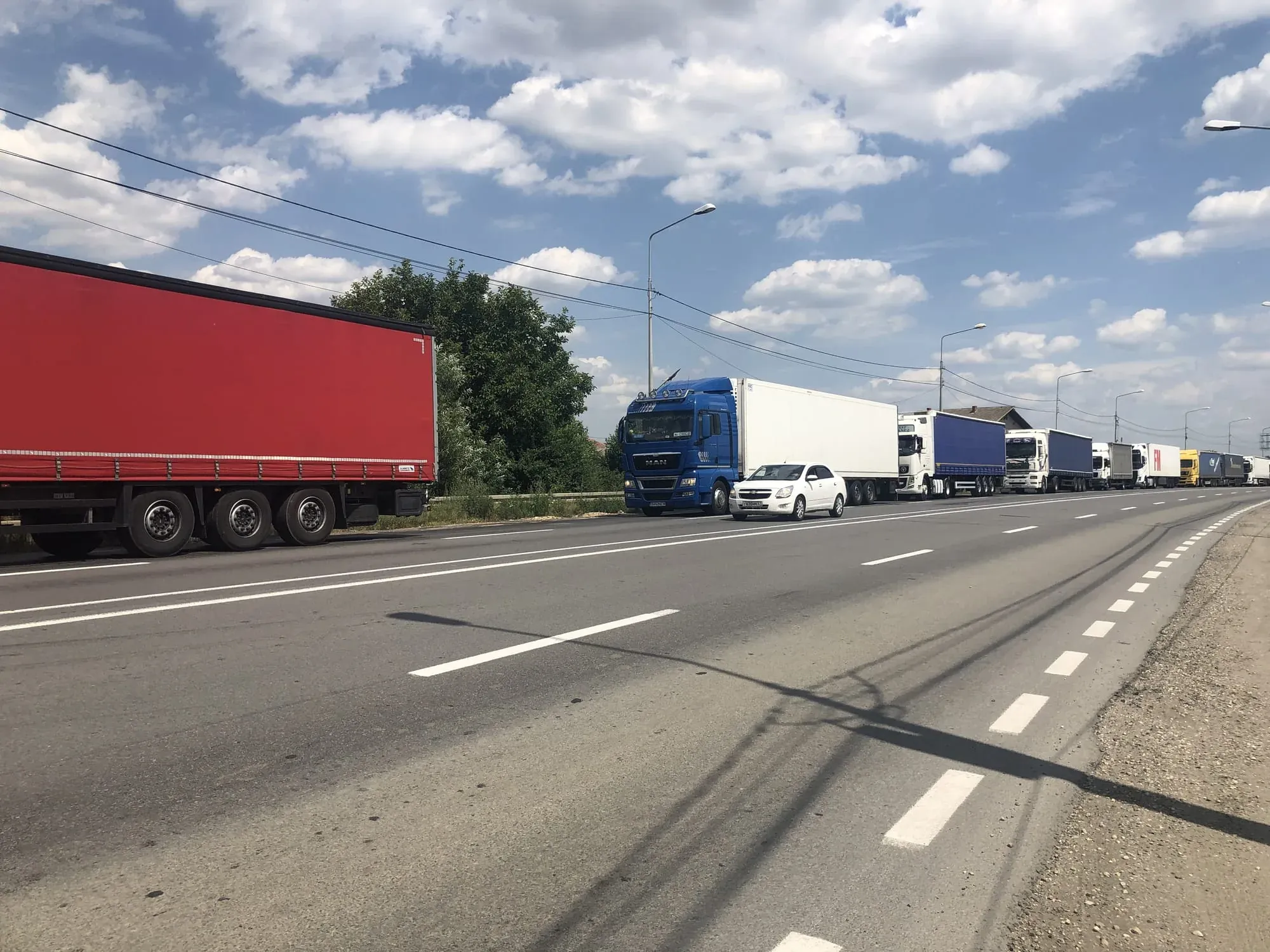 Highway with trucks and cars, blue DAF truck prominent in traffic