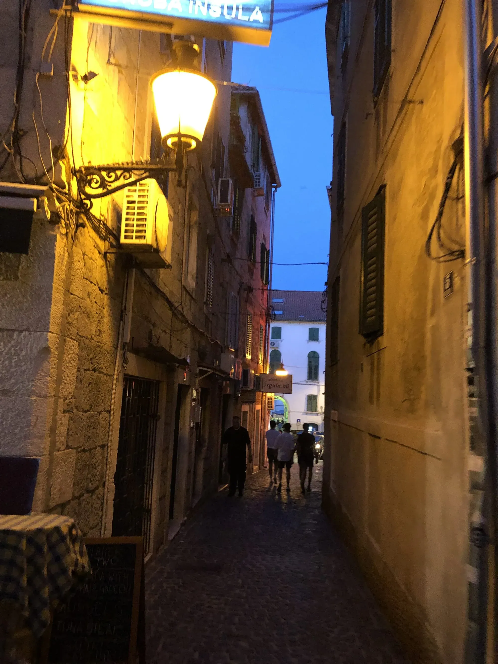 Evening alley in historic town center with lit street lamp and stone buildings