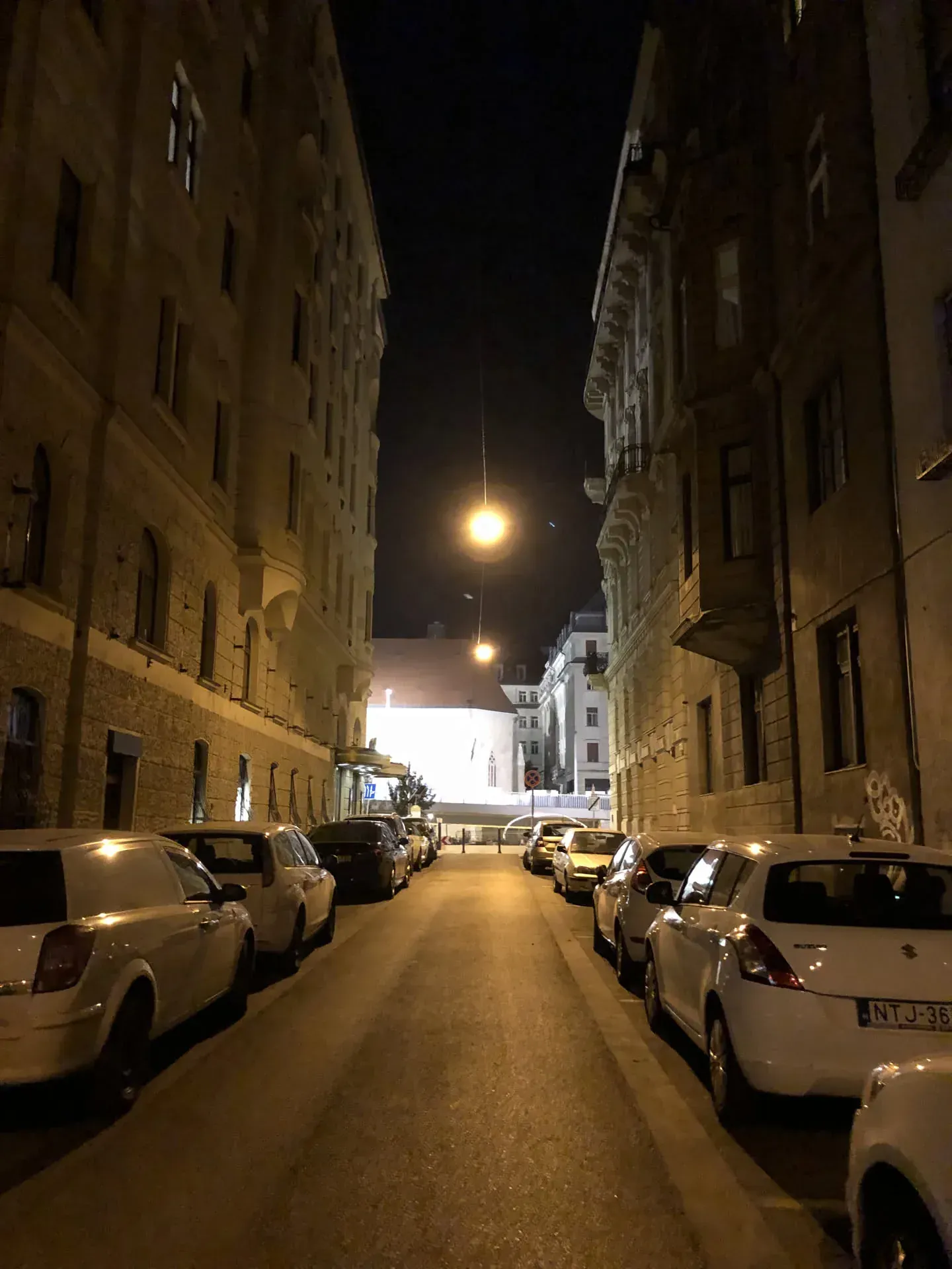 Night street in Belváros with parked cars and lit buildings
