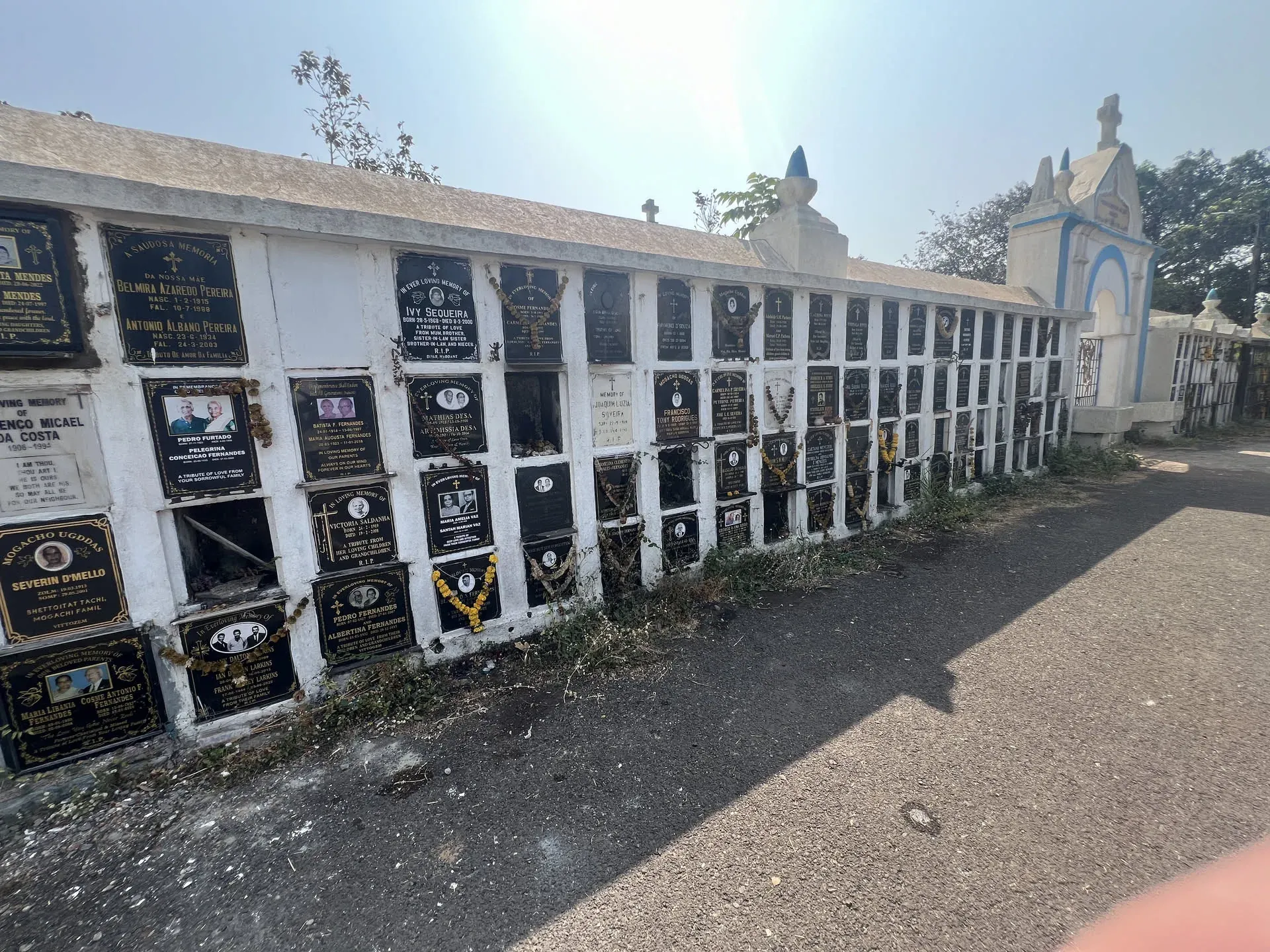 White-walled cemetery with black plaques at Navelim