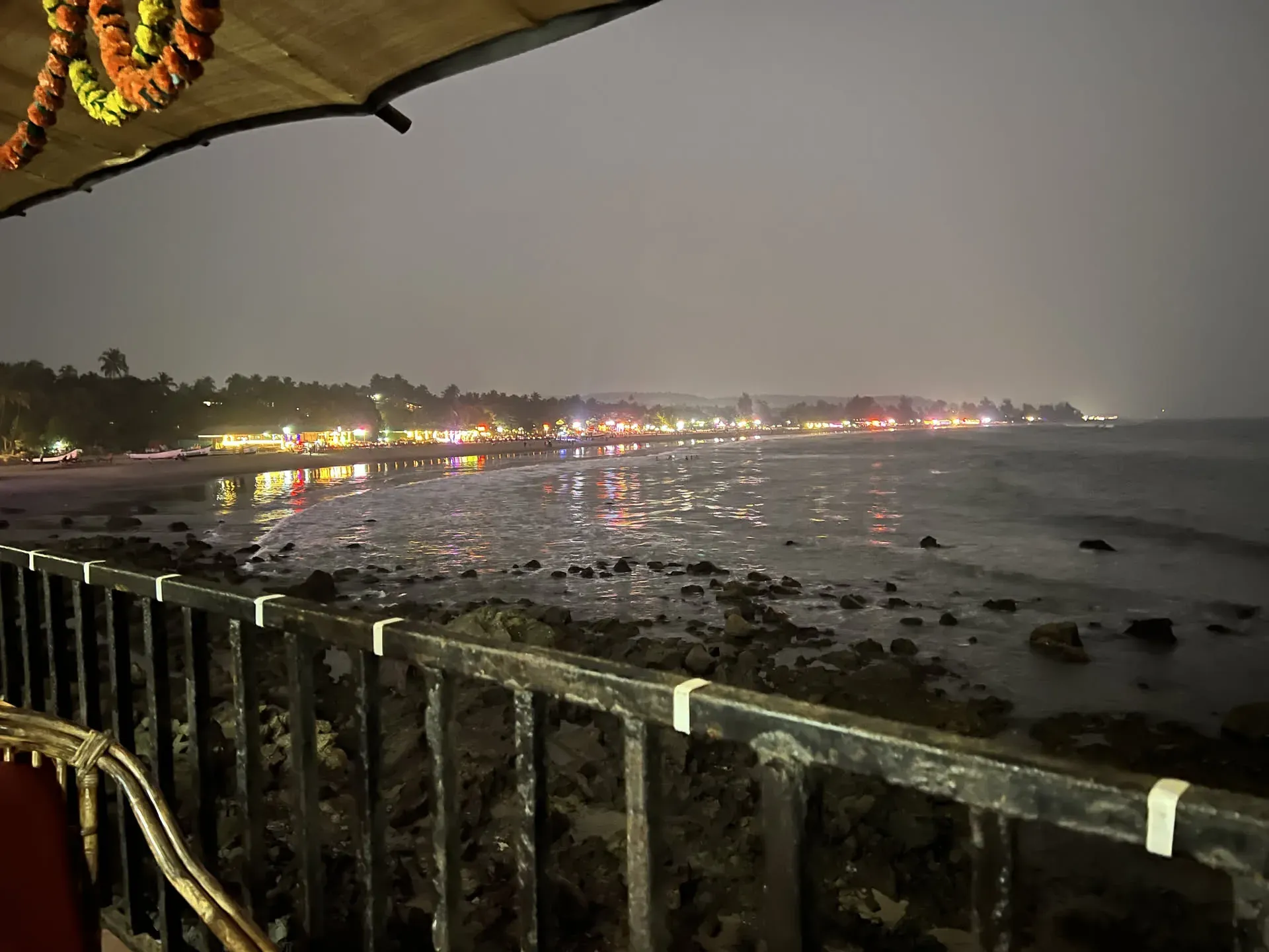Lit beach shacks at night, Querim