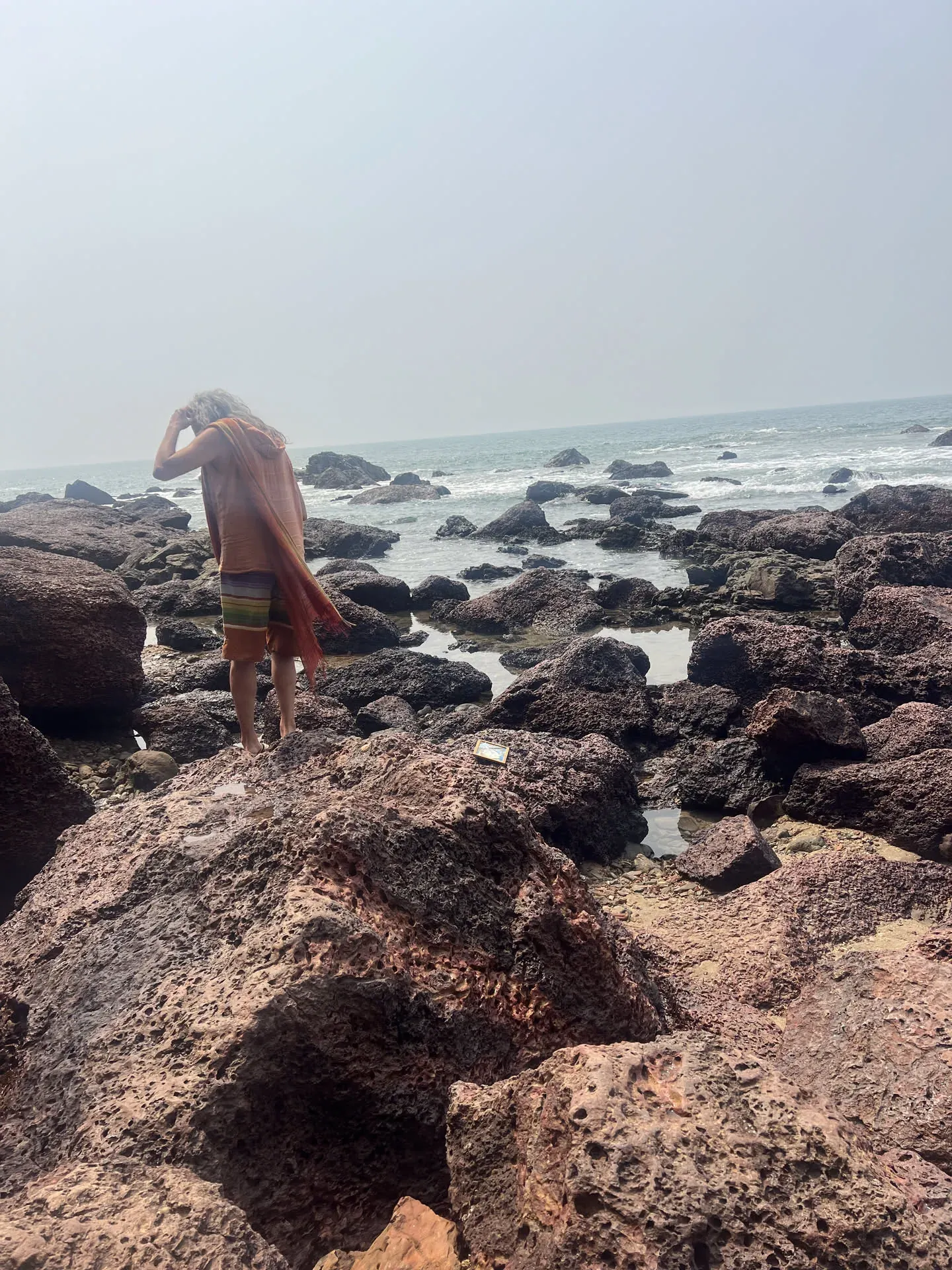 Person photographing rocky coastline at Querim