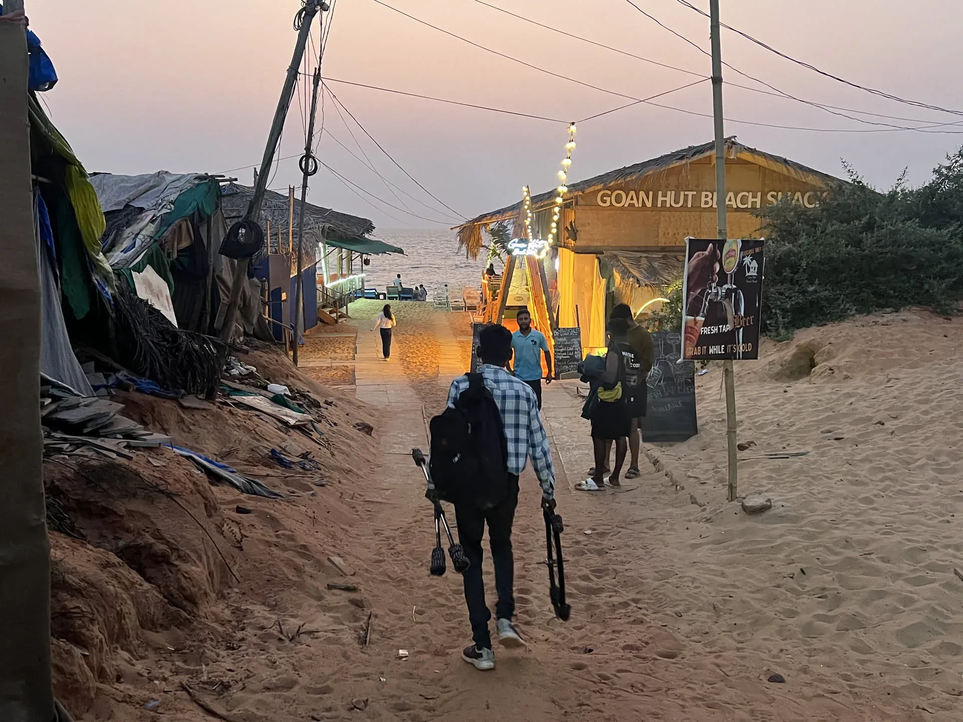 Person on bicycle at Marquis Vaddo beach shack at dusk
