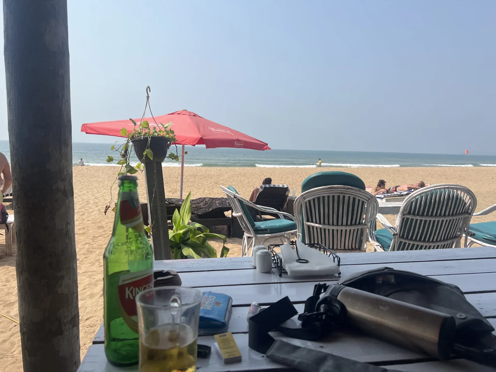Green beer bottle on beach table with ocean view