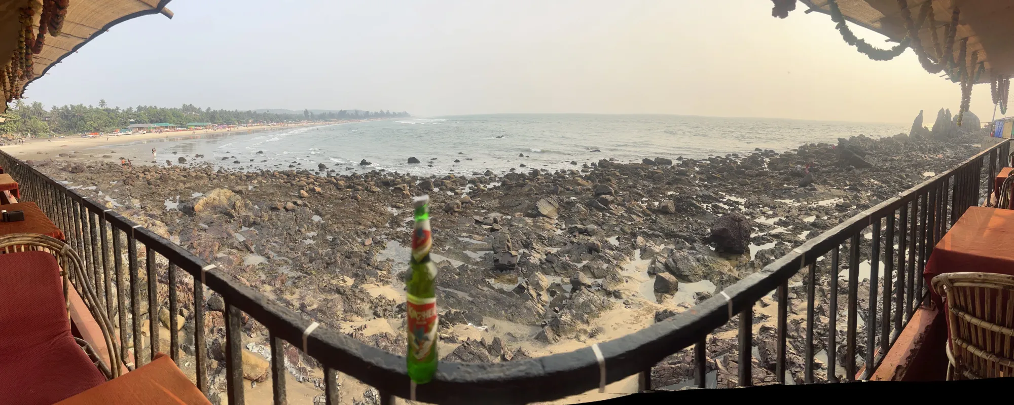 Beer bottle on railing at Querim beach