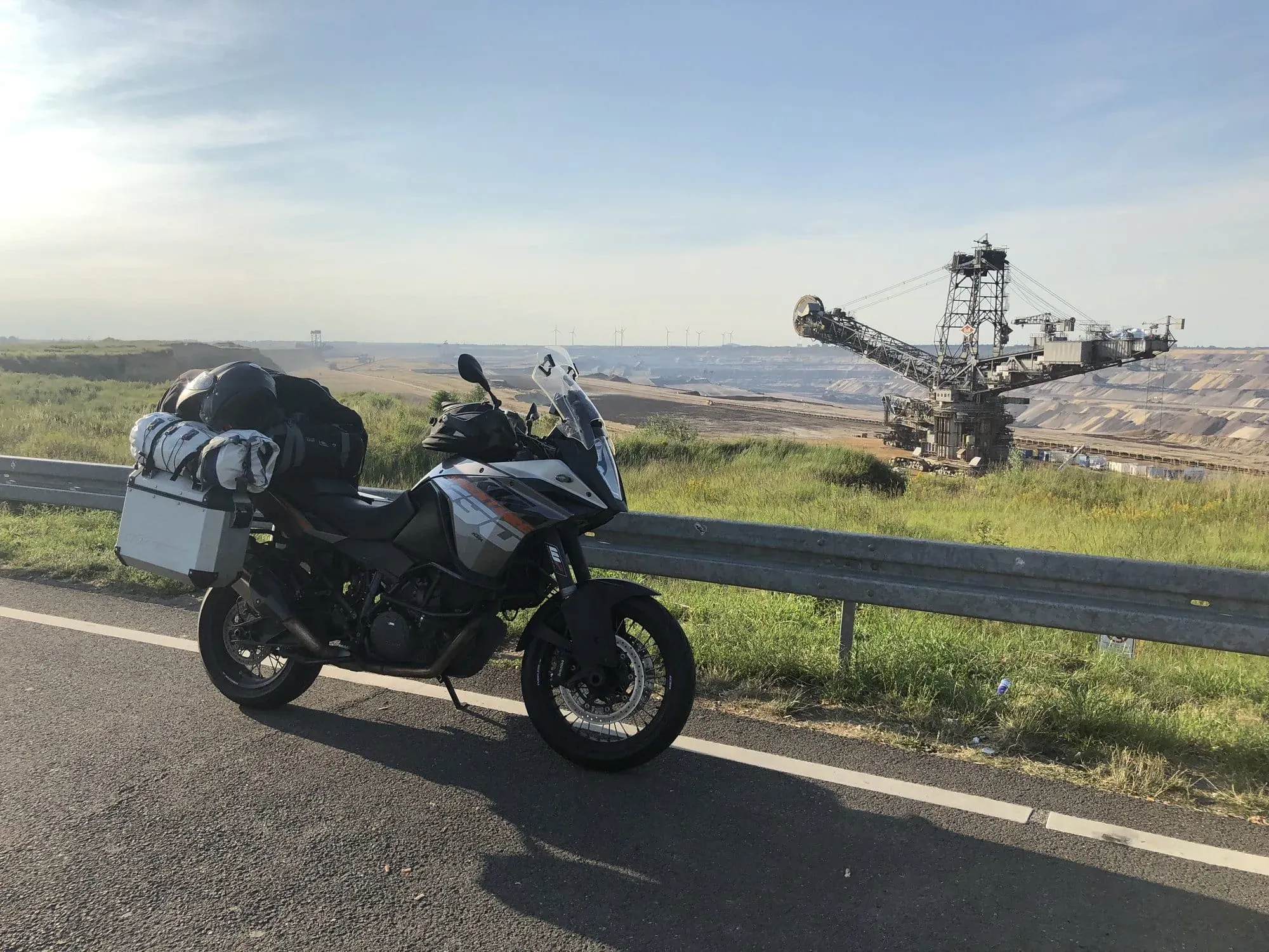 Motorcycle with luggage parked overlooking open-pit mining landscape