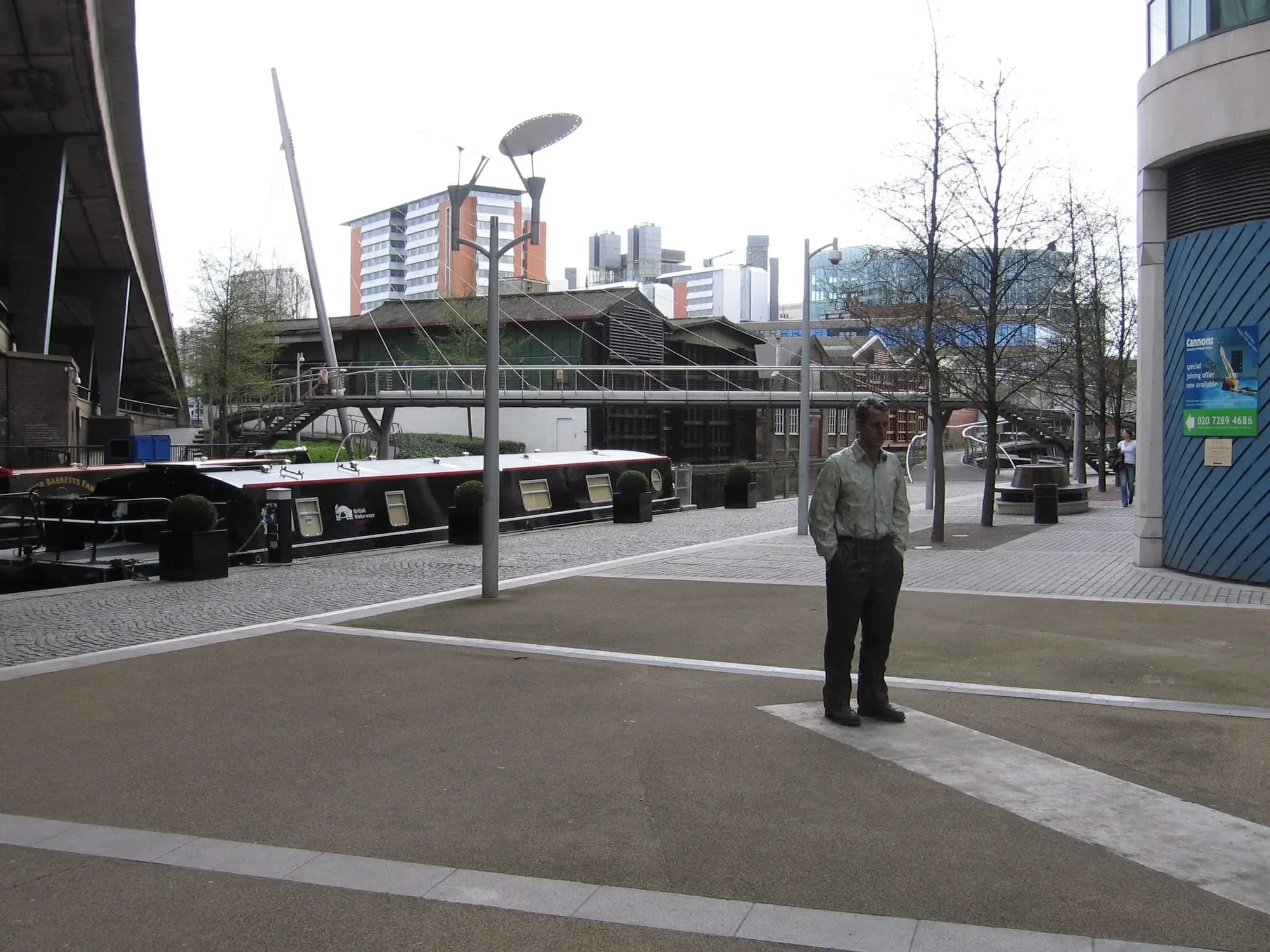 Modern waterfront development with statue and footbridge over canal basin