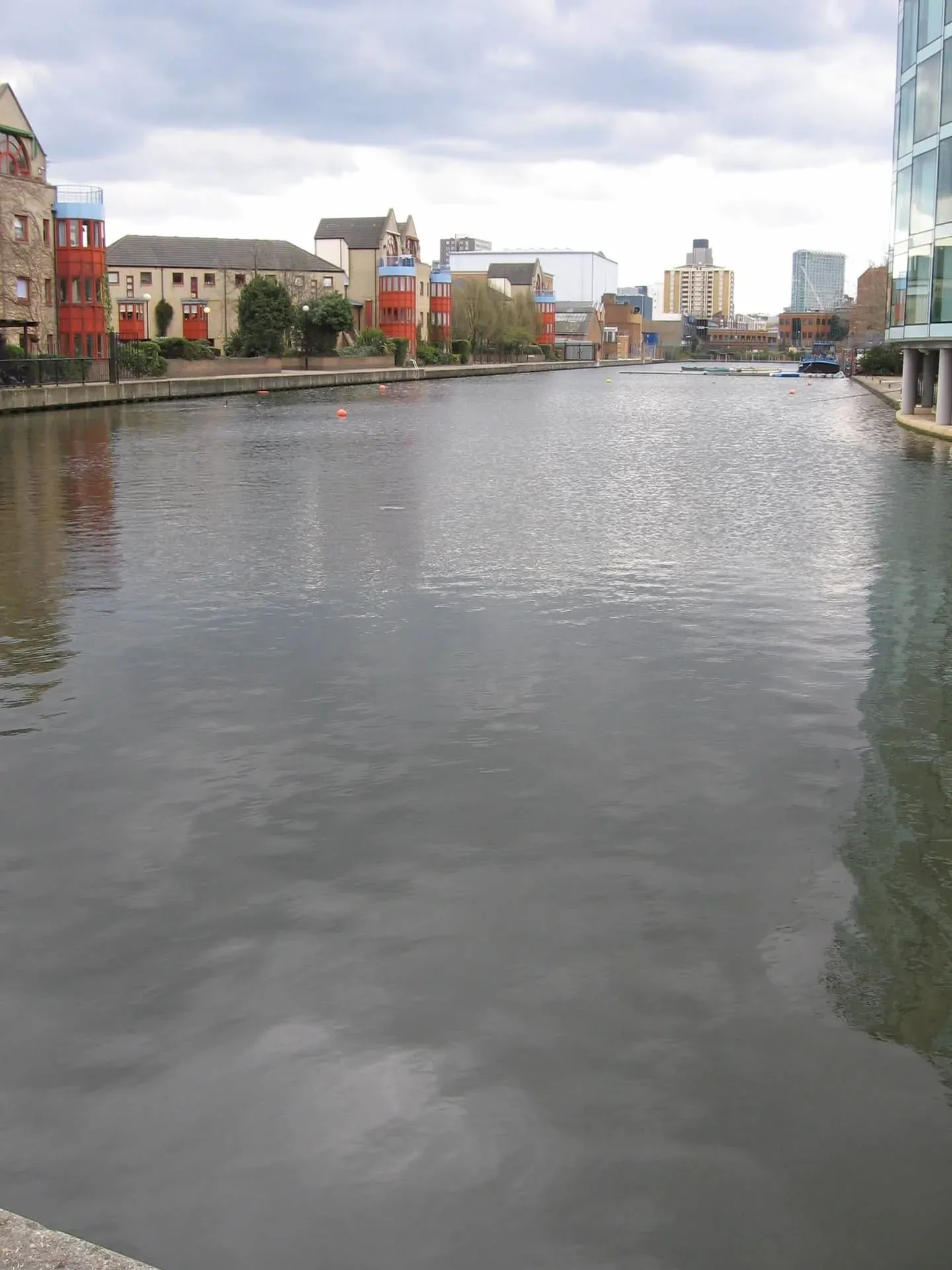 Calm canal waterfront with colorful converted warehouse buildings and modern skyline