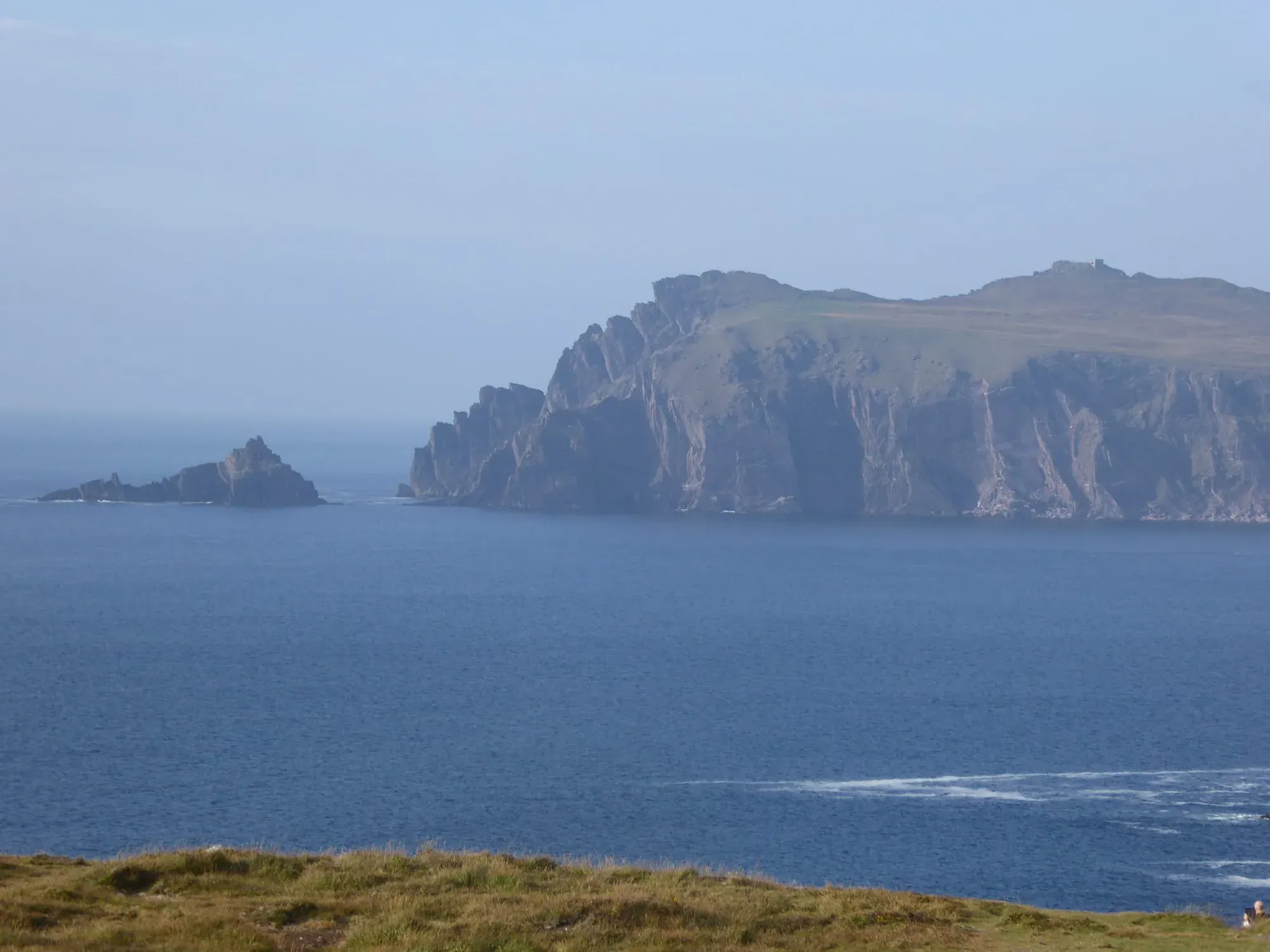 Tall columnar basalt cliffs with small islands in blue water below