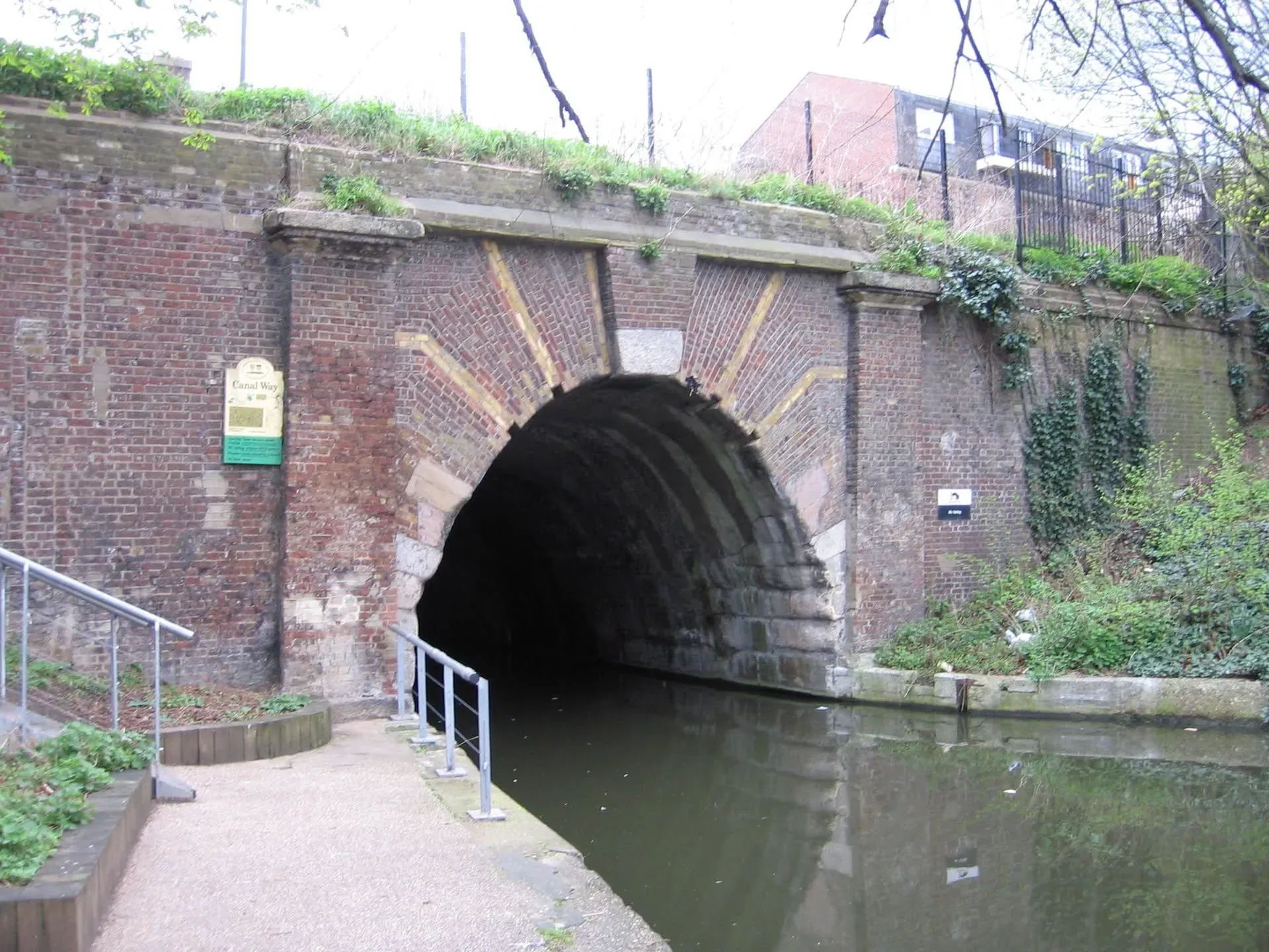 Brick tunnel entrance on canal with information plaque on wall above