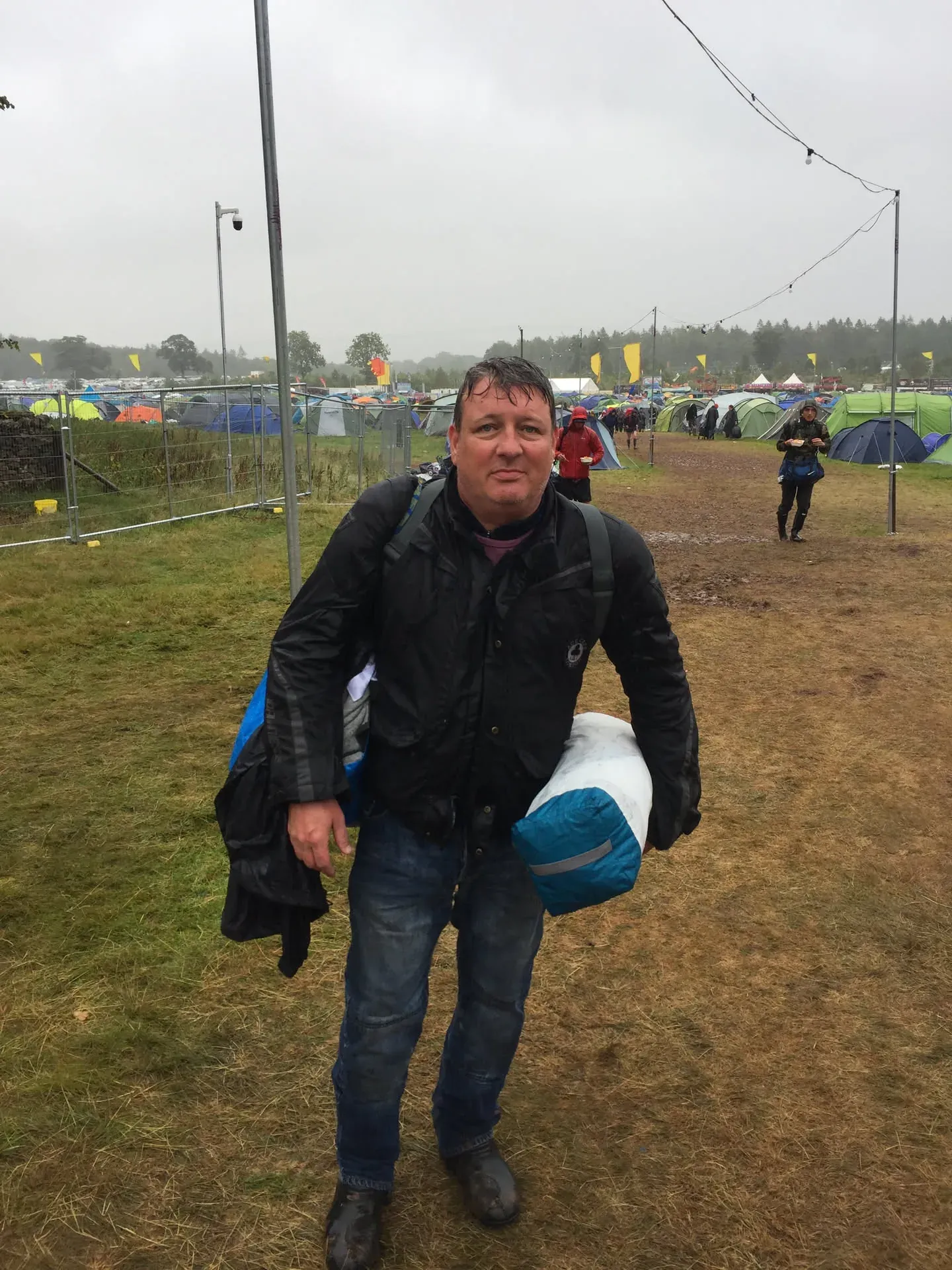 Man holding sleeping bag at Lowther festival campground