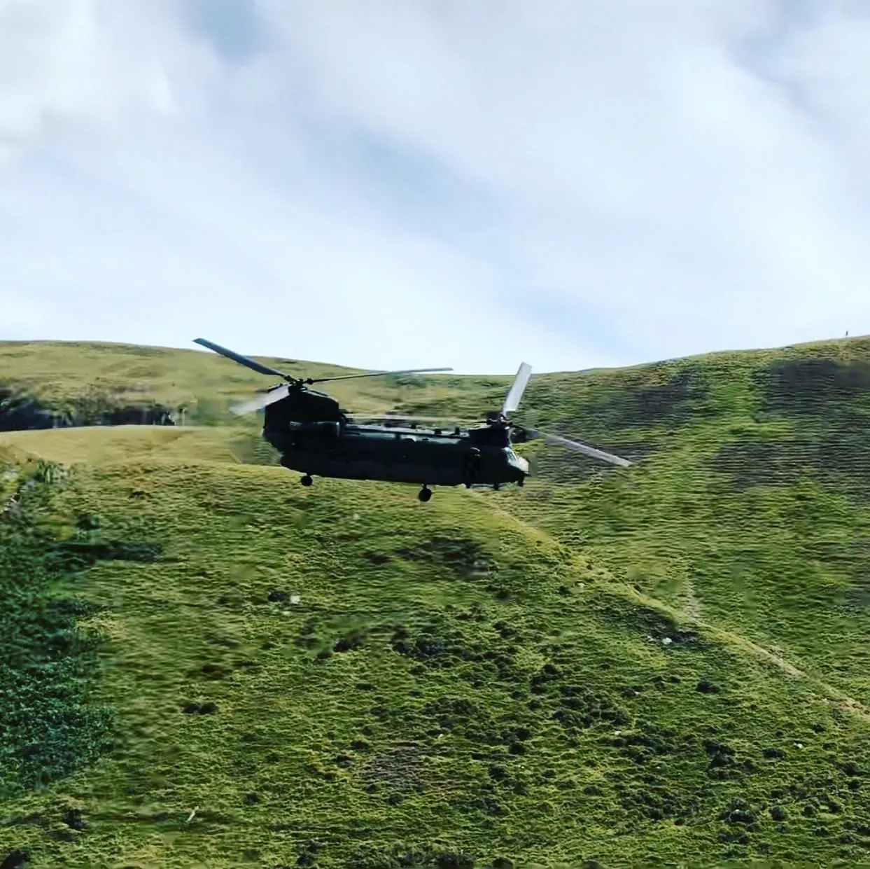 Military helicopter flying over green hills near Dolgellau, Wales