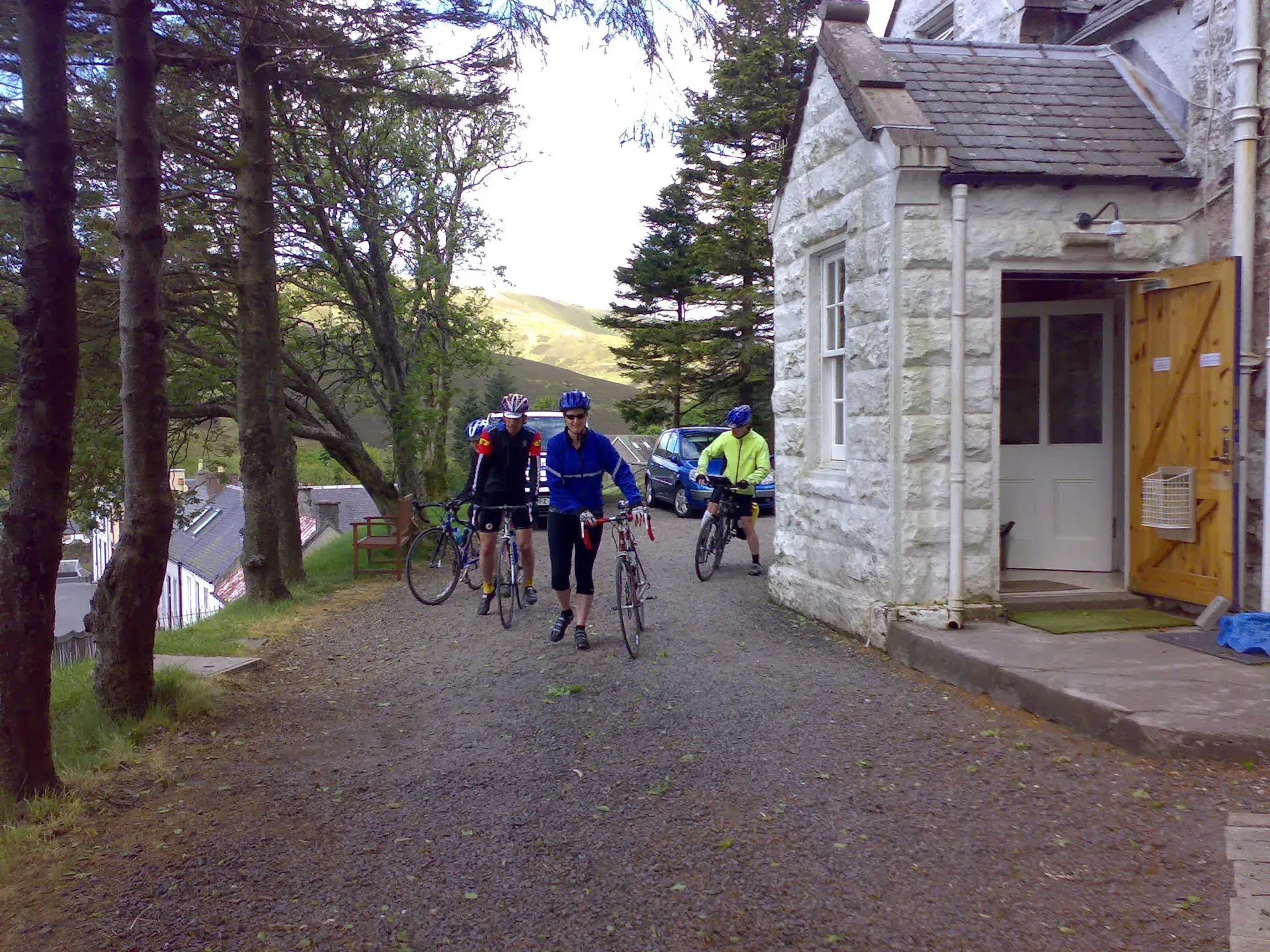 Cyclists passing stone cottage at Wanlockhead, Scotland