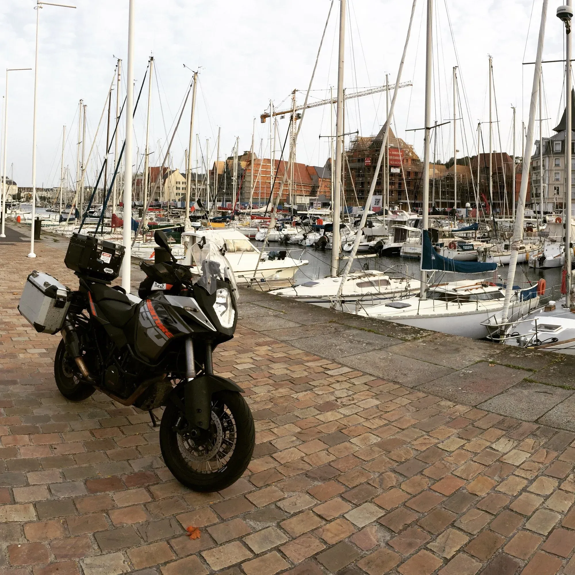 Black scooter parked at Deauville marina sailboats
