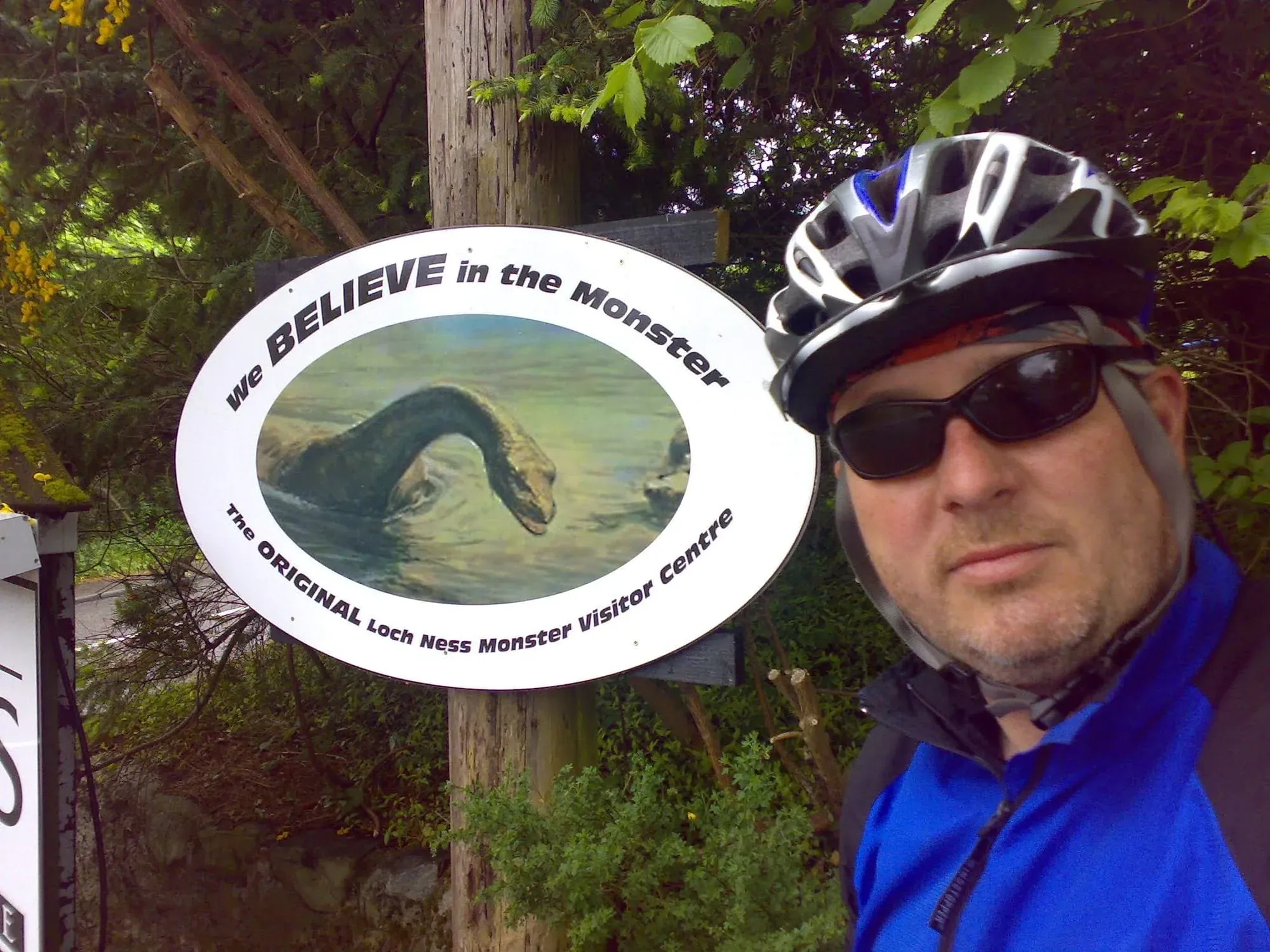 Cyclist posing with Loch Ness Monster visitor center sign