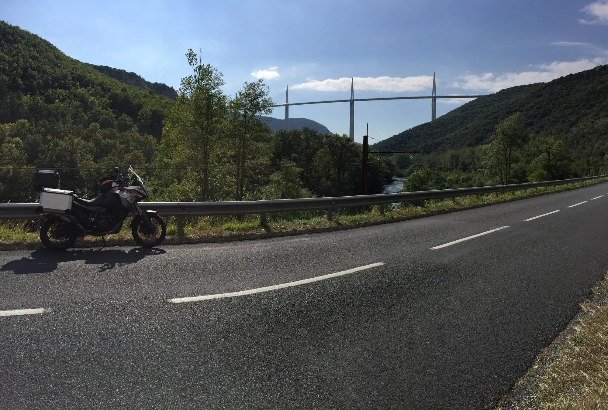 Motorcycle parked on highway overlooking river and cable-stayed bridge