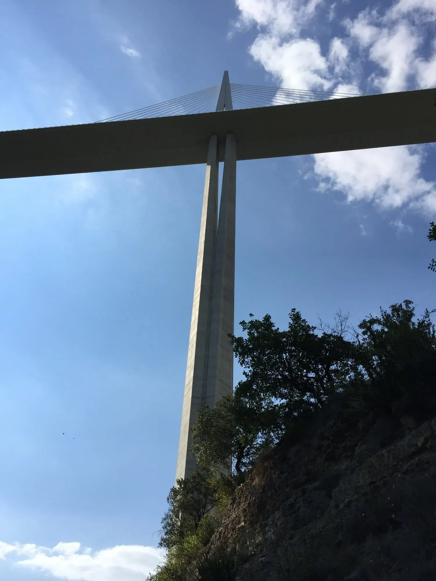Modern cable-stayed bridge tower against blue sky with clouds