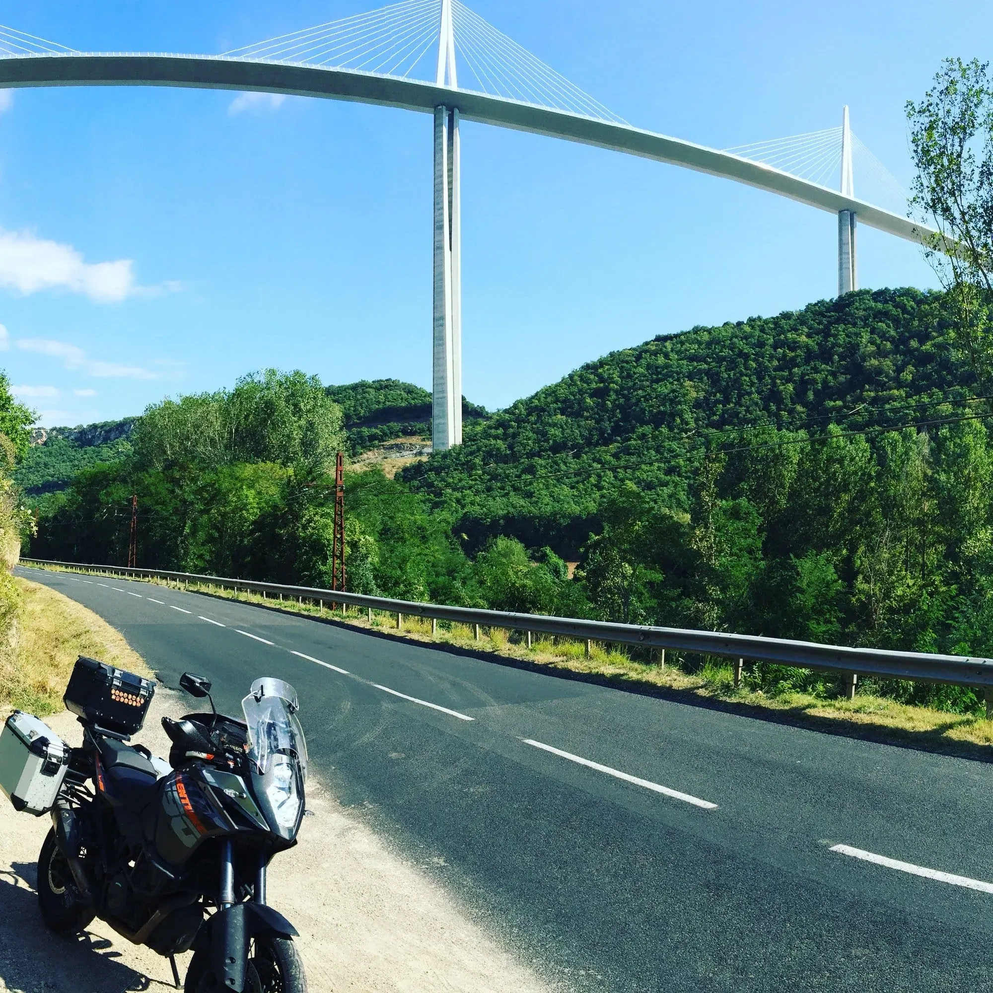 Motorcycle parked near highway beneath modern cable-stayed bridge