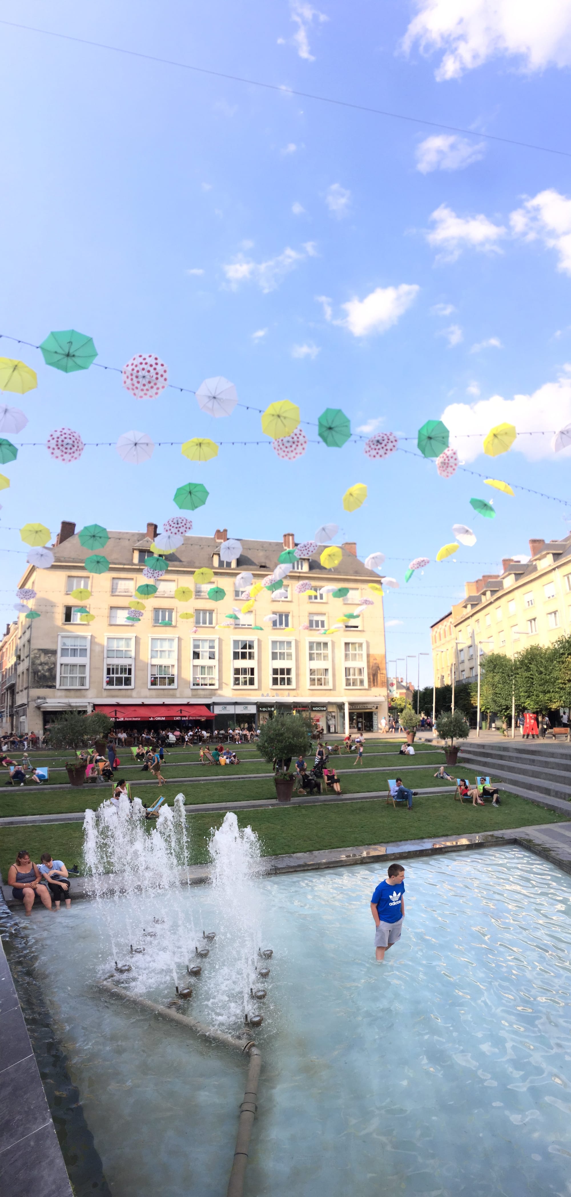 Colorful umbrellas strung above Amiens square fountain