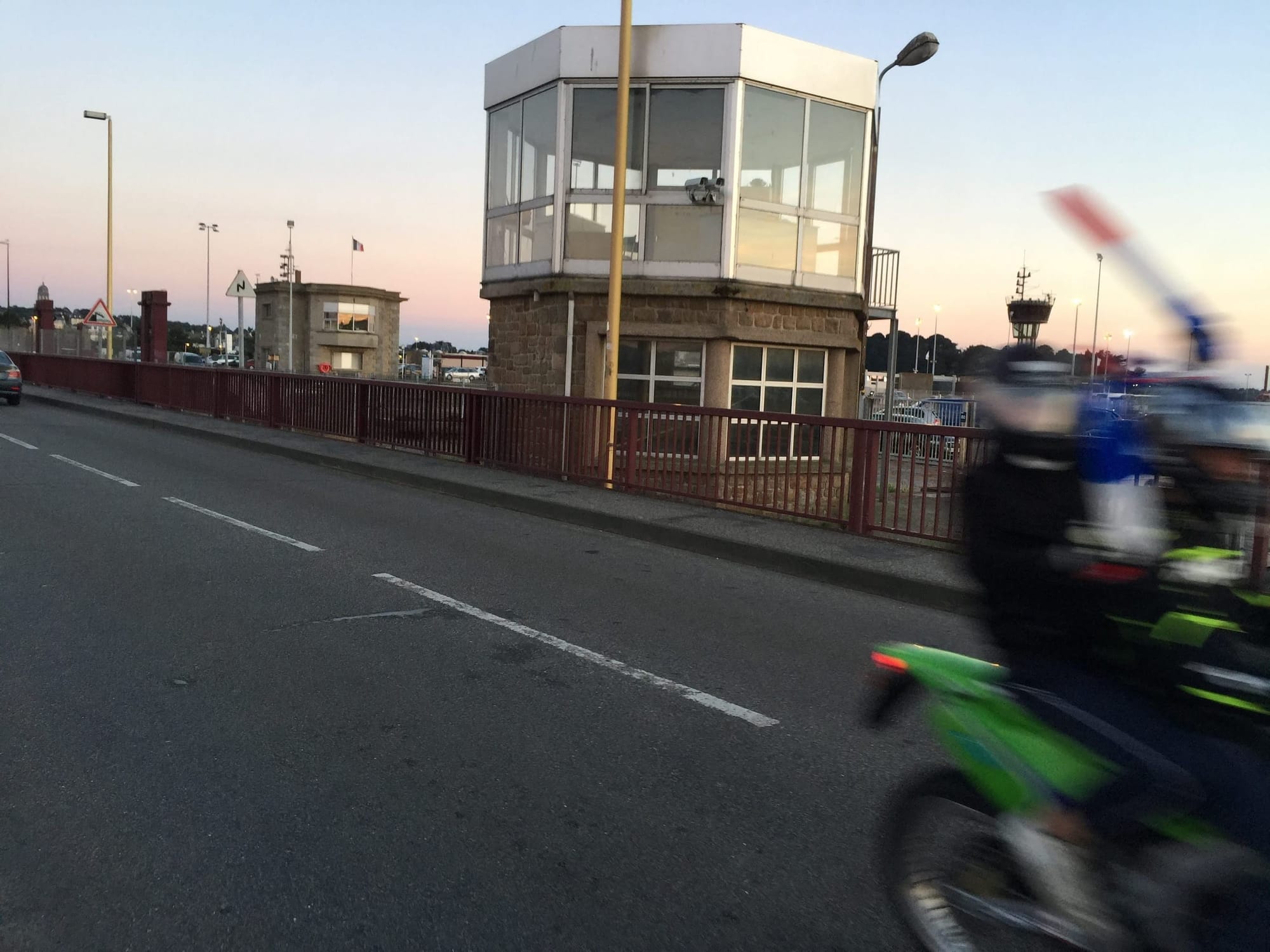 Bridge toll booth with motorcyclist passing at dusk