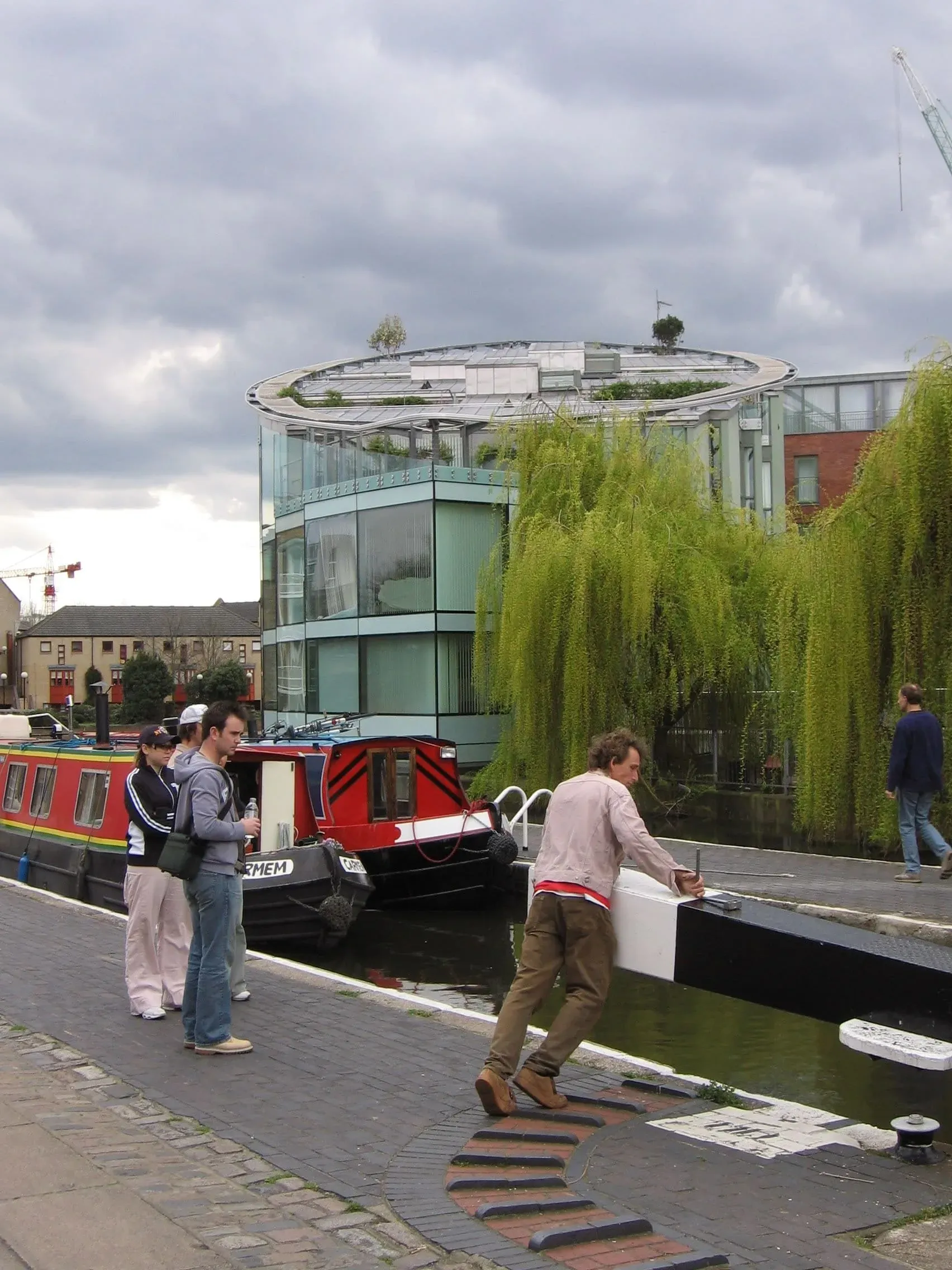 Modern circular building beside canal with narrowboat and people on towpath