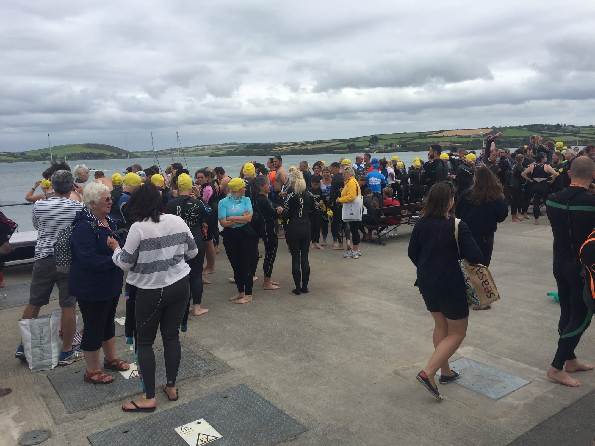 Large group of swimmers in yellow caps at Padstow beach