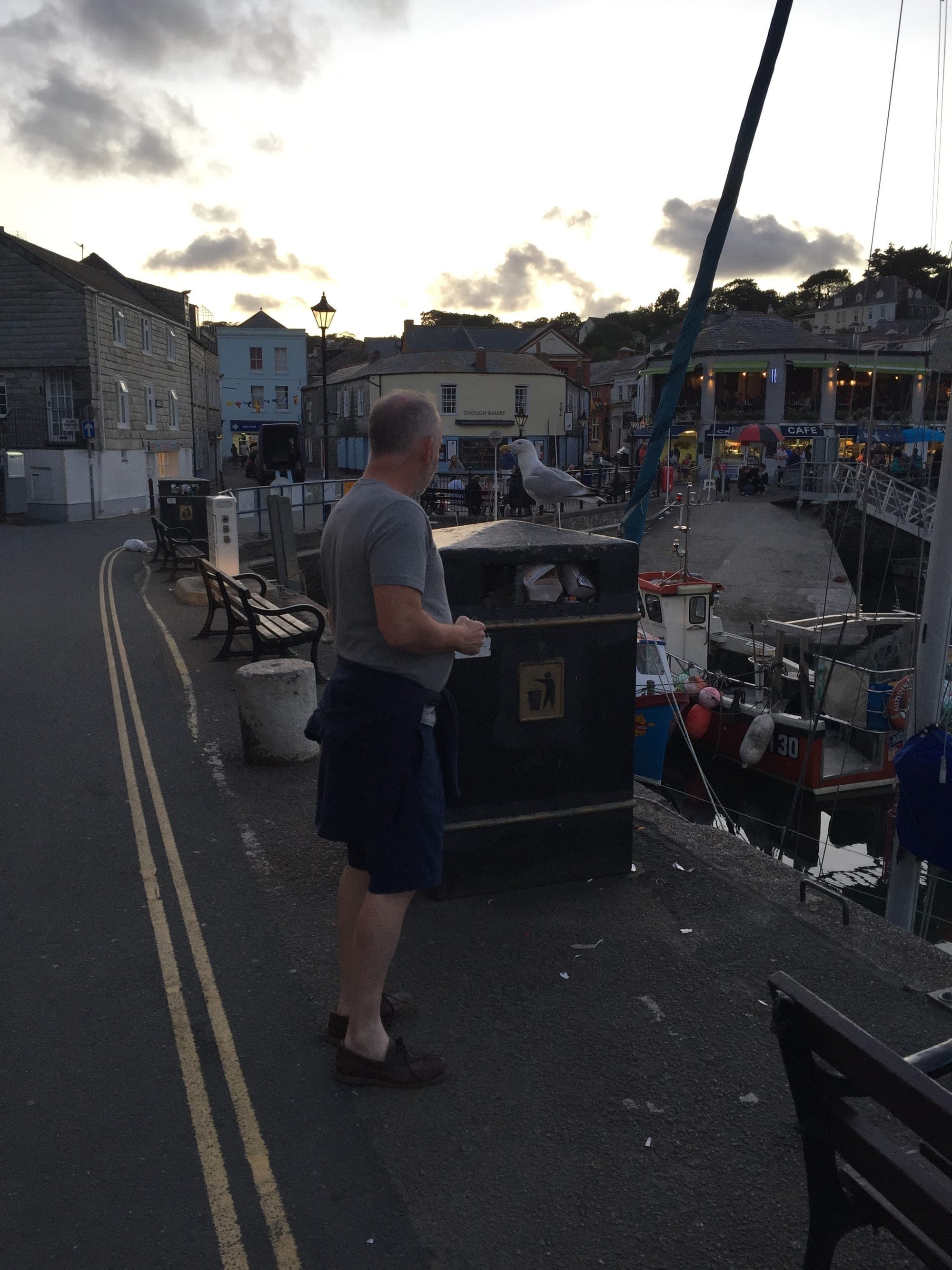 Man at trash bin, Padstow harbor at dusk