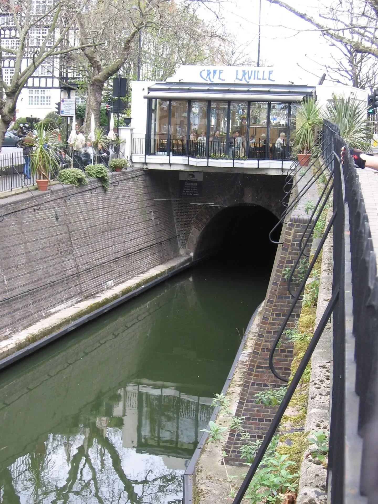 Modern white cafe building spanning over canal tunnel entrance