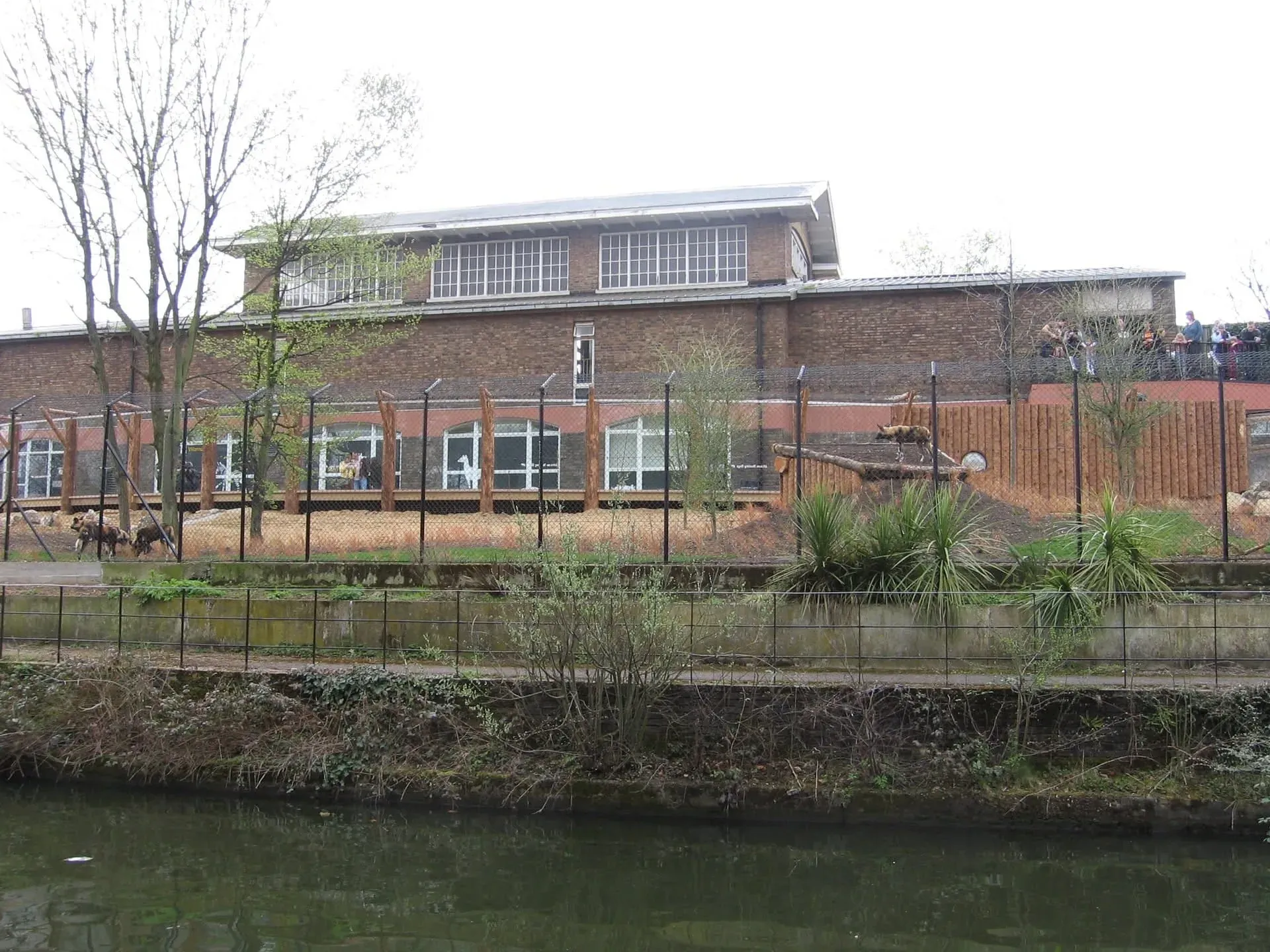 Modern brick waterside building with wooden fence beside calm canal water