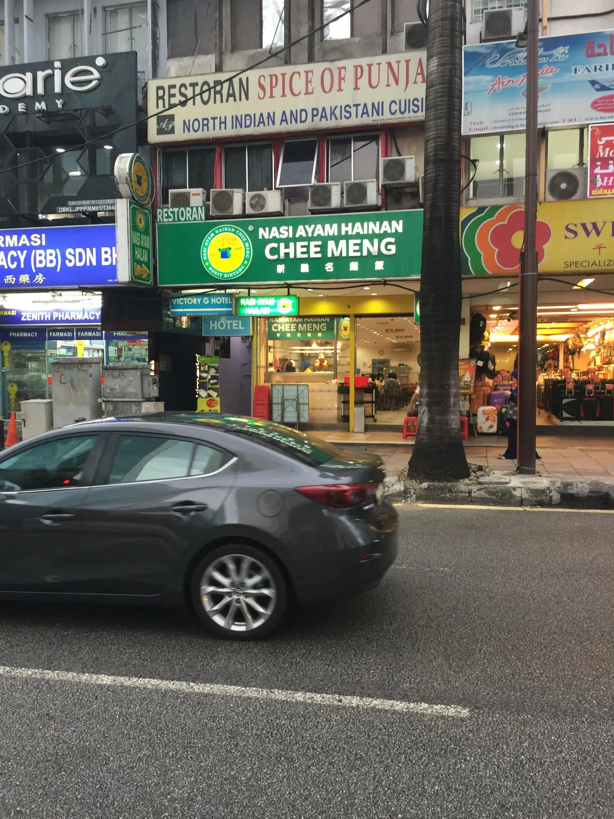 Street view of Asian restaurants and shops with parked car