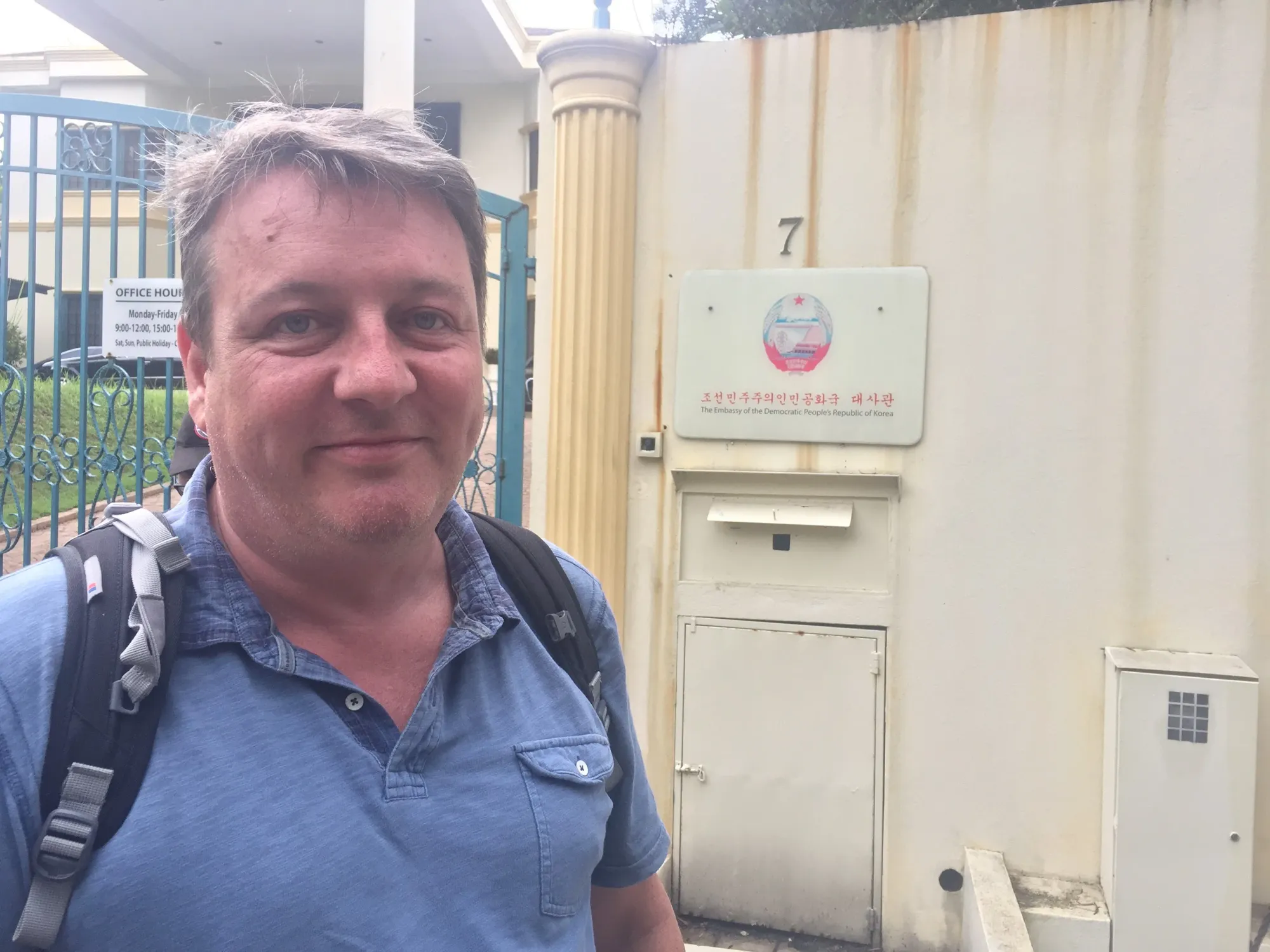 Man in blue shirt outside embassy building