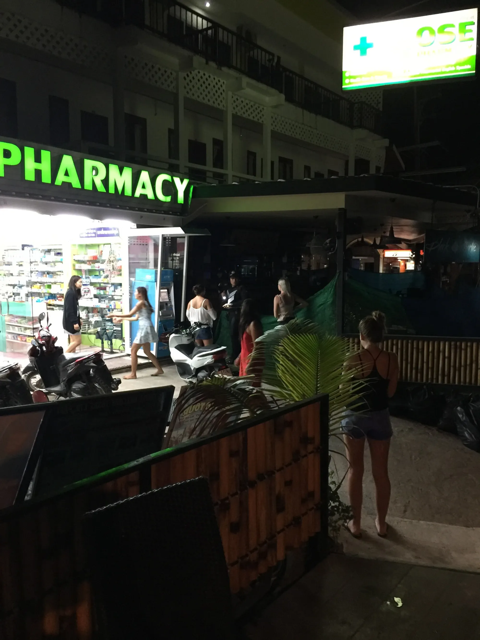 Pharmacy storefront at night with customers outside
