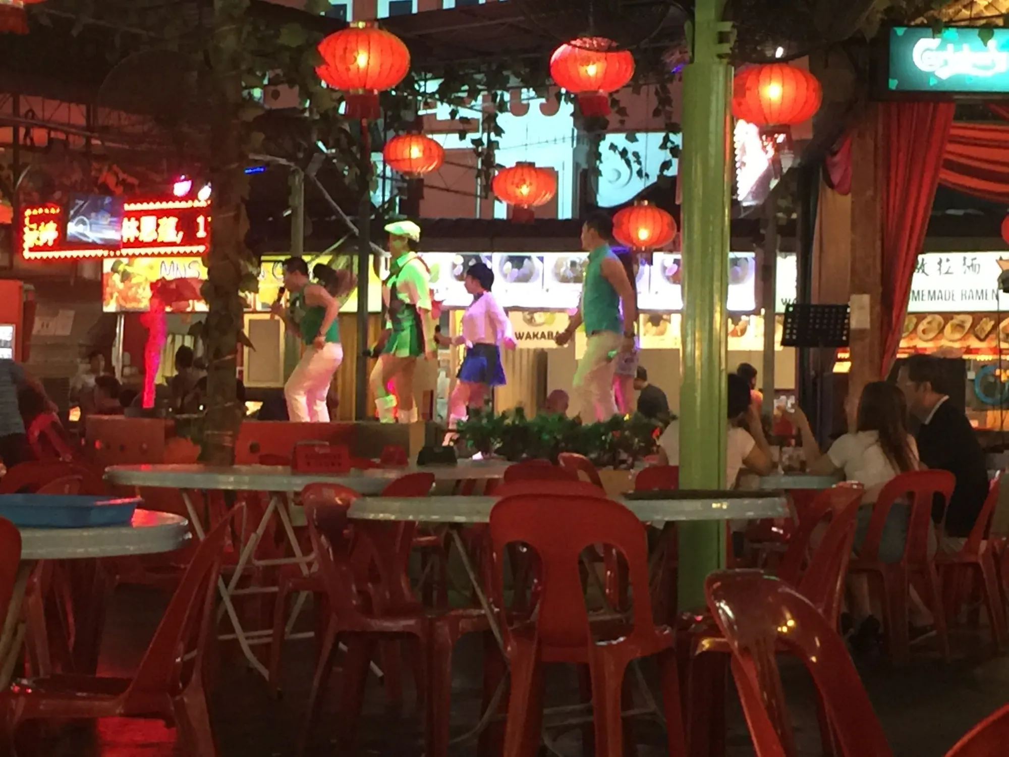Performers dancing on stage in neon-lit bar