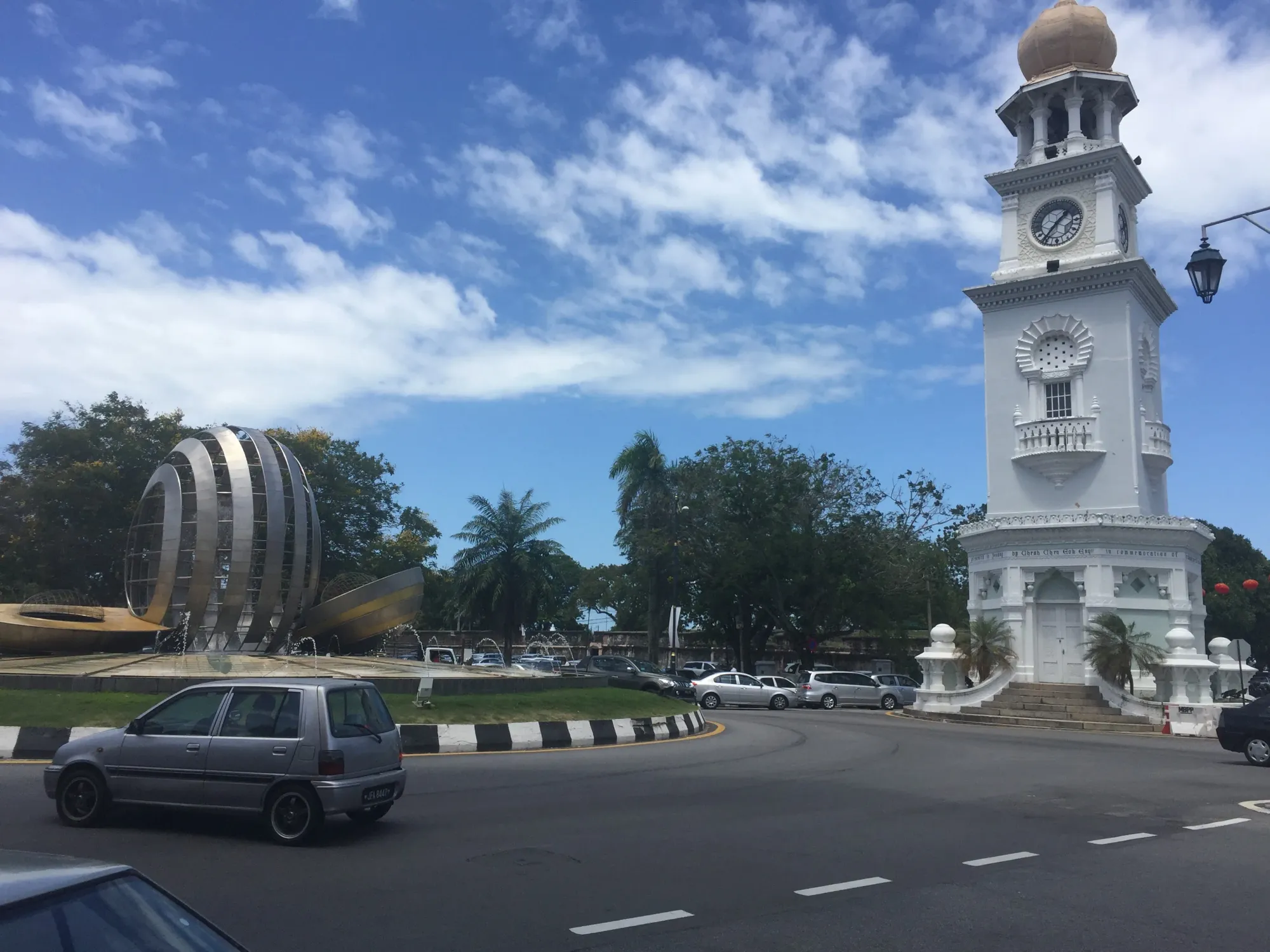 White clock tower and modern spherical sculpture in plaza