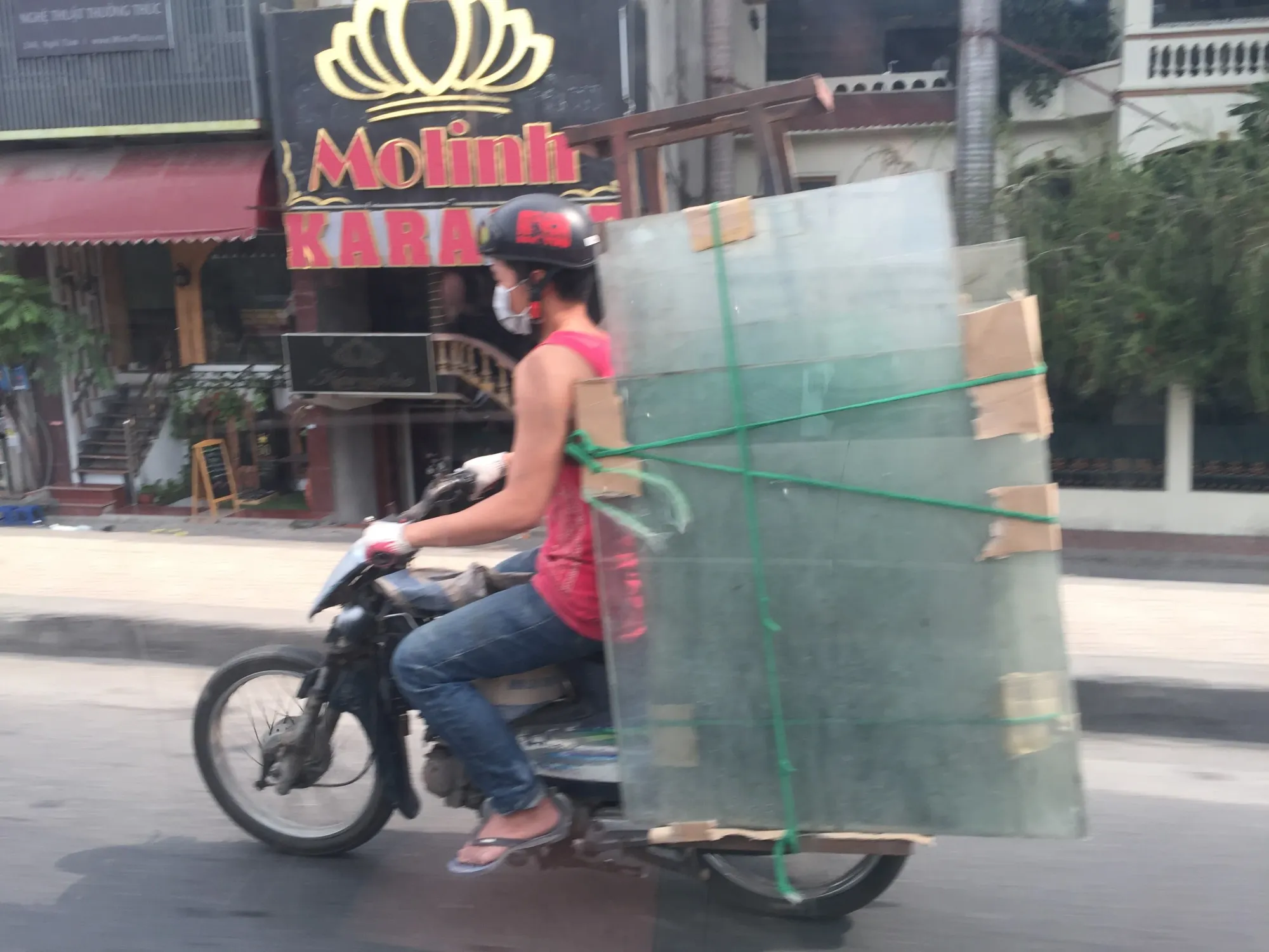 Person on motorcycle with large cargo trailer on street