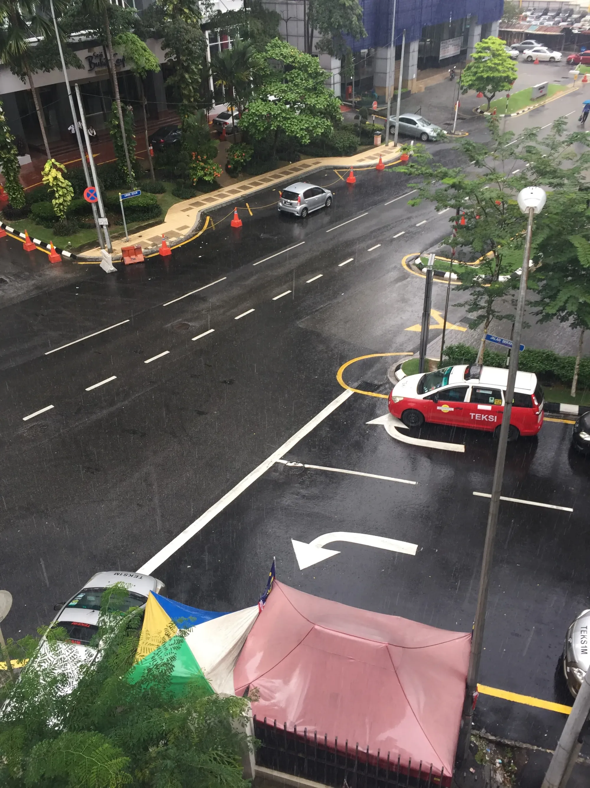 Aerial view of wet street with red taxi and construction cones